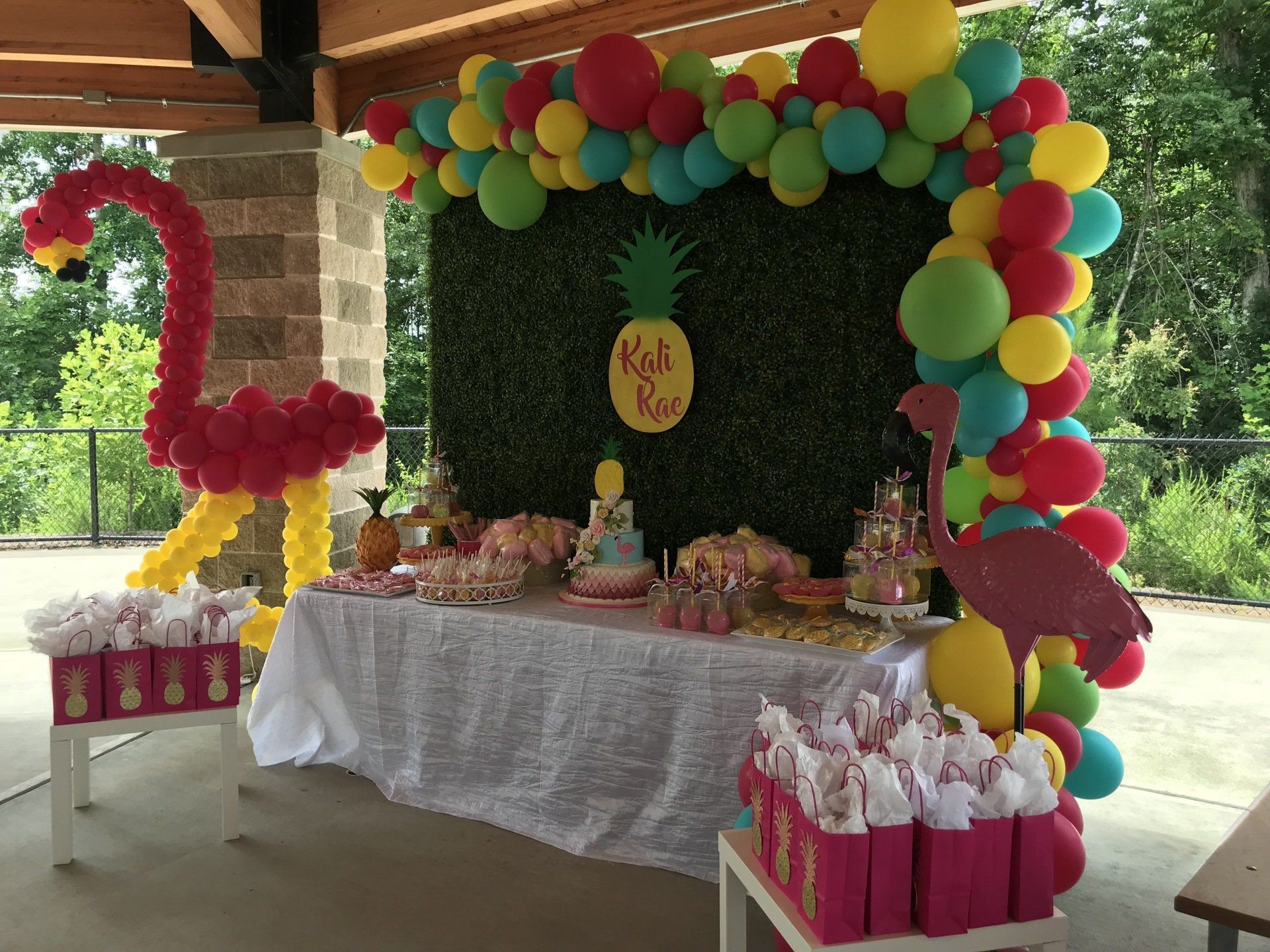 Tropical flamingo themed kids party backdrop with rainbow balloon arch and dessert table
