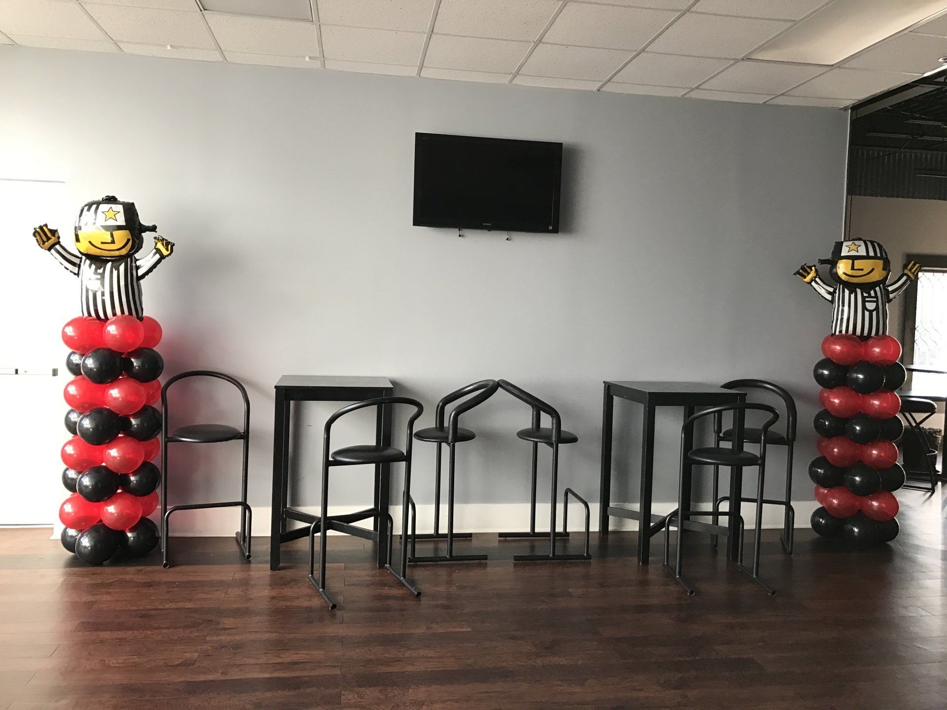 Two black and red balloon columns topped with a cartoon style referee.