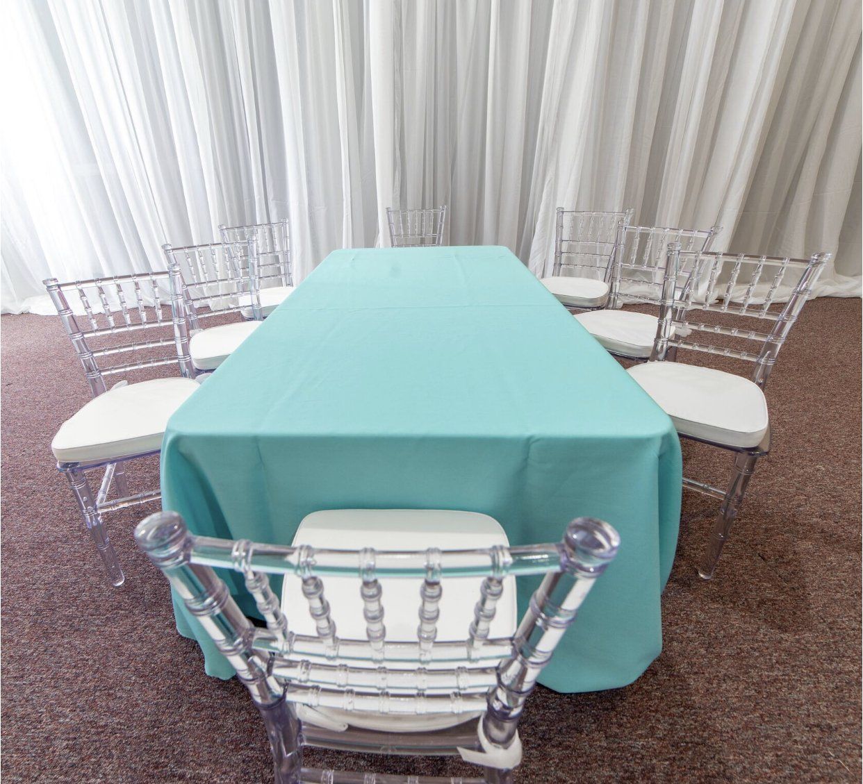 Simple kids party table setup with teal linen and clear chairs for DIY styling