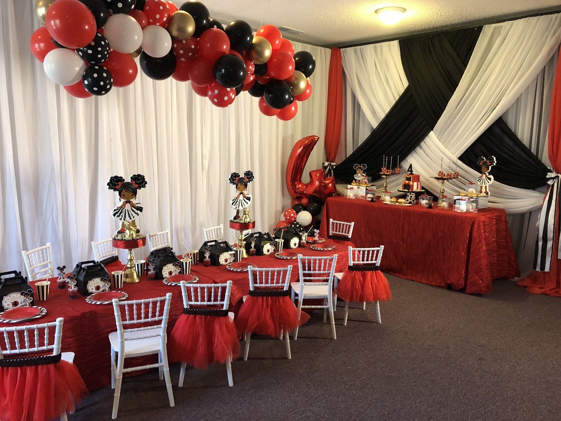 Red black and white Minnie Mouse themed kids party with balloon garland and dessert table