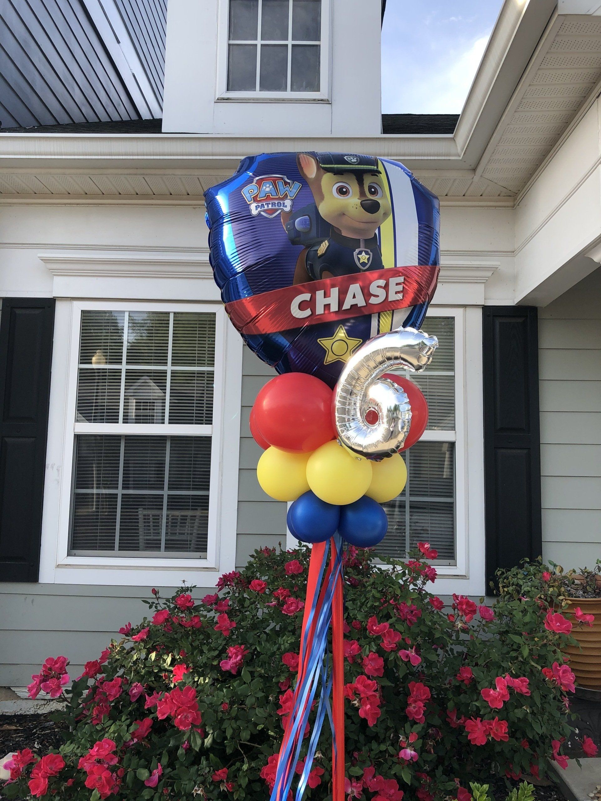 Paw Patrol Chase character foil balloon with red and blue balloon base for kids birthday yard decor in front of home