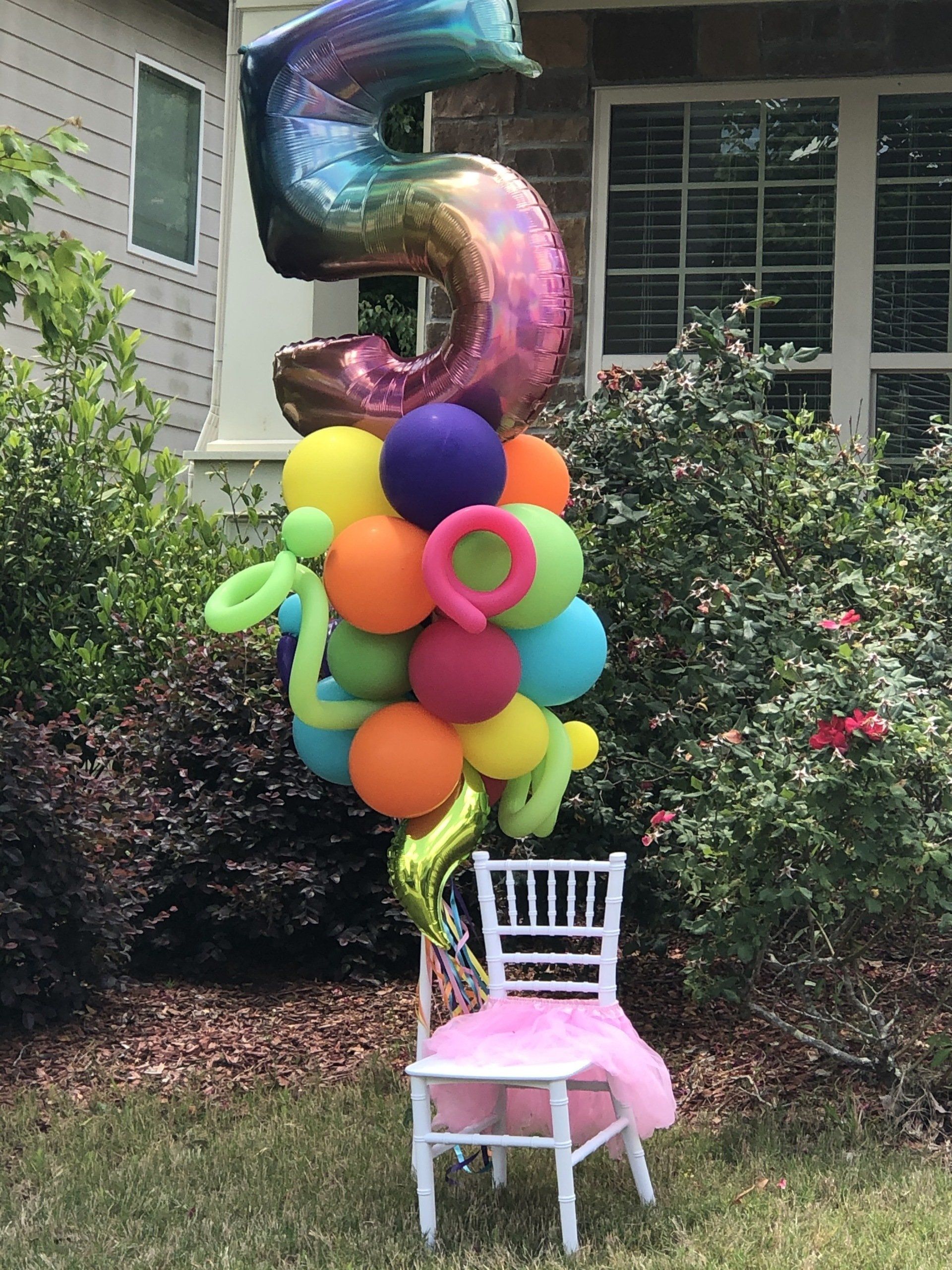 Large iridescent number five balloon with bright colorful balloon cluster for outdoor birthday party