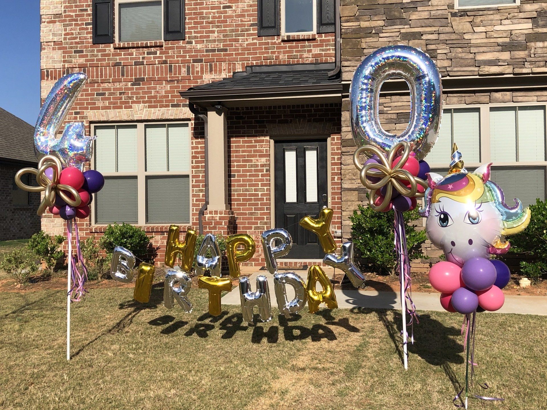 Birthday yard balloon display with silver numbers, unicorn, and colorful clusters