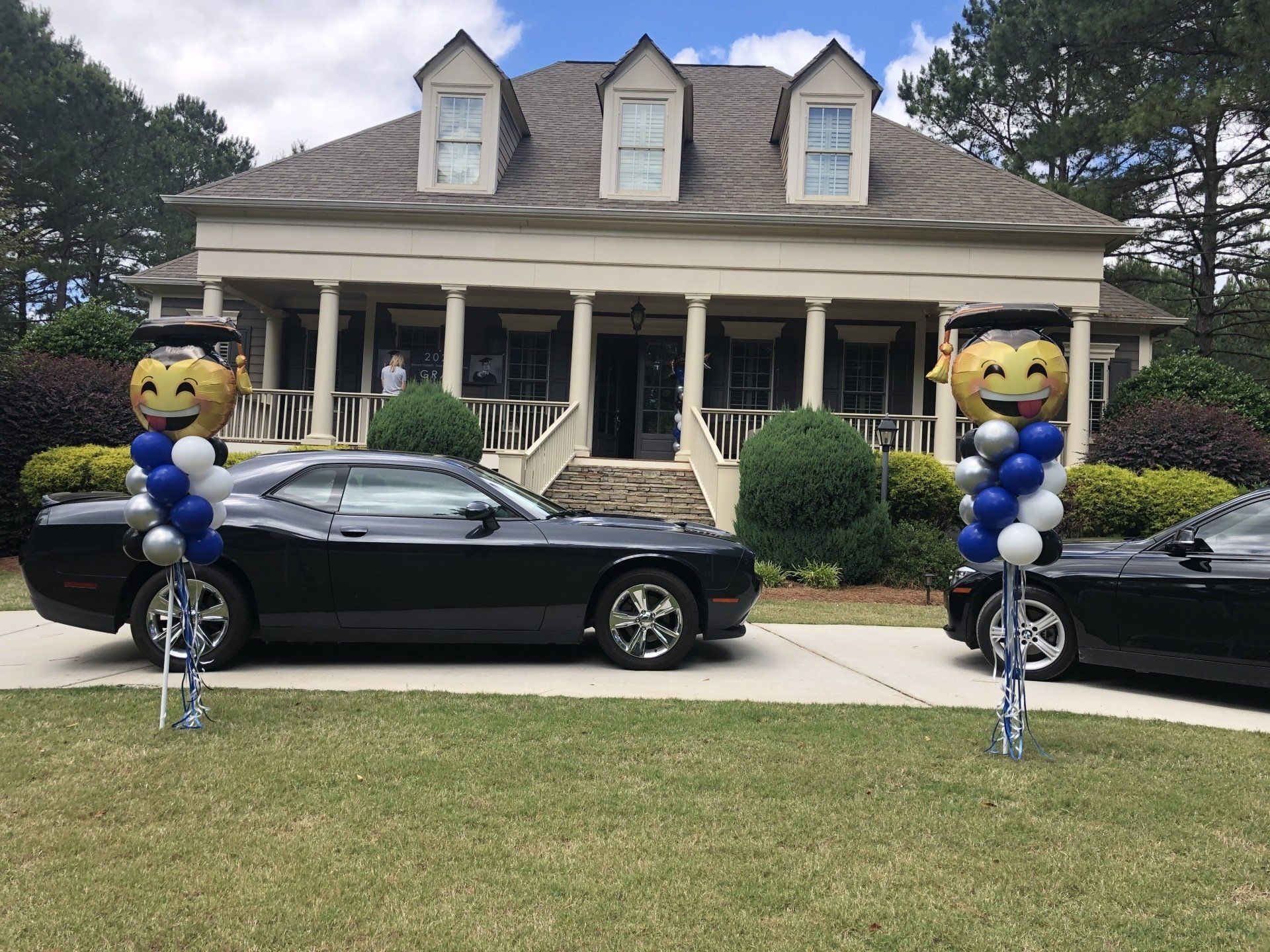 Outdoor graduation balloon emoji towers set on both sides of driveway in front of house