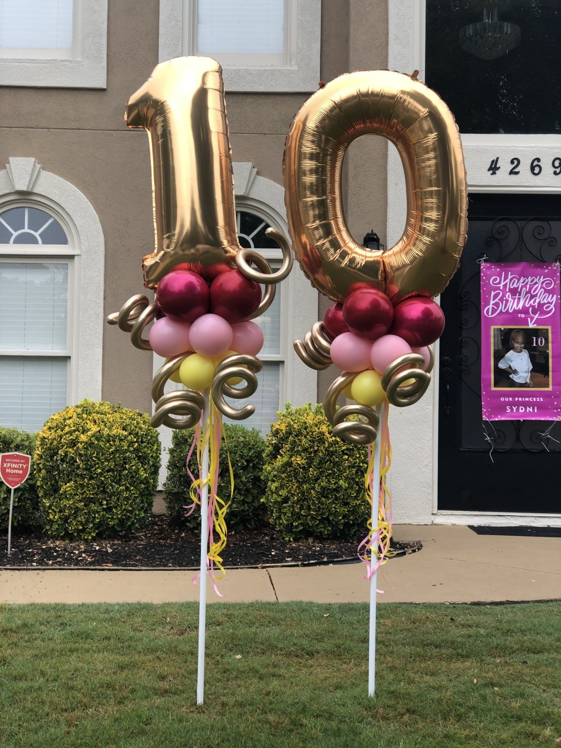 Large gold number ten balloons with pink and burgundy balloon base for birthday yard decor