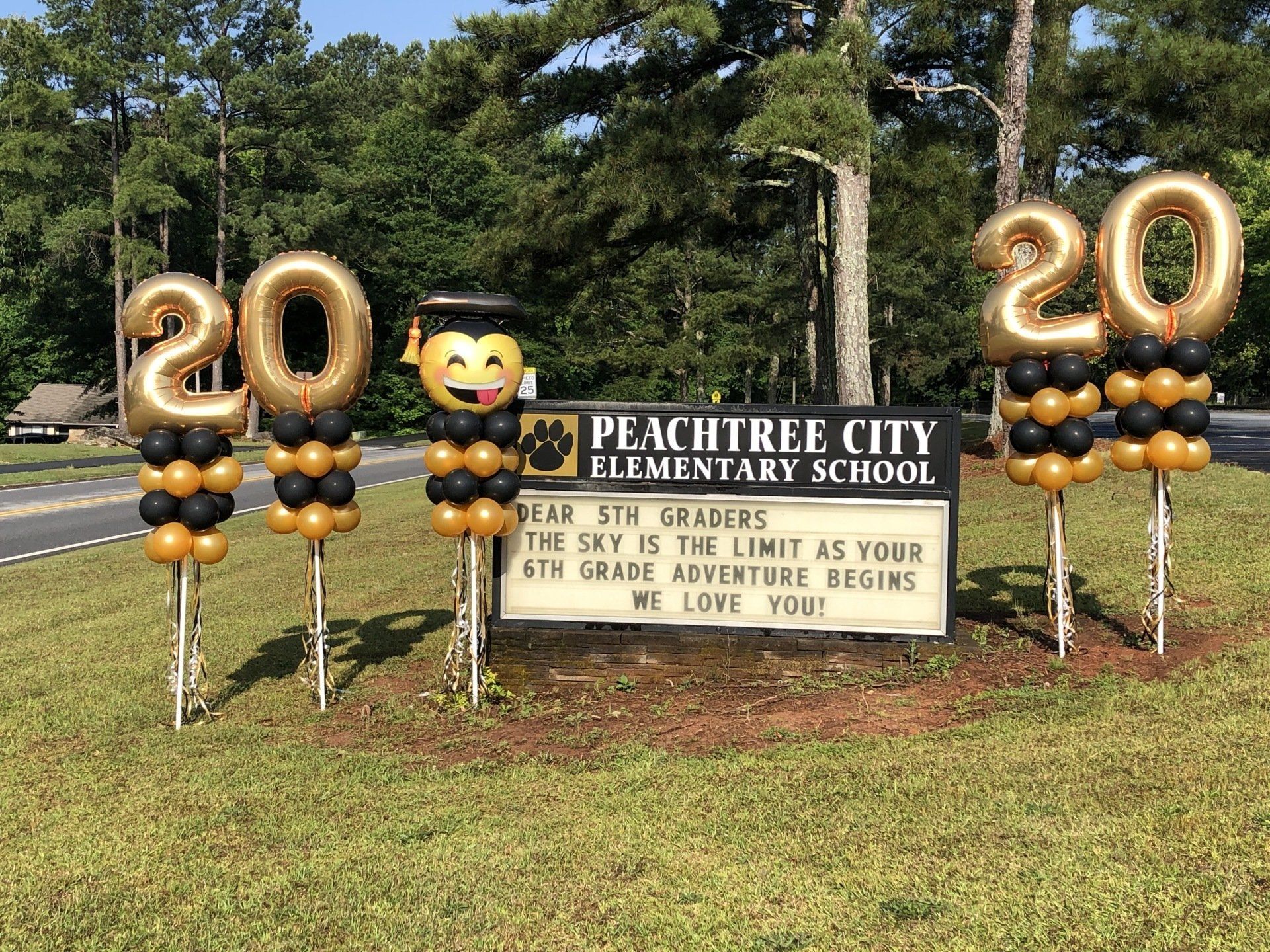 Graduation yard balloon display with gold number twenty balloons and school sign for outdoor celebration