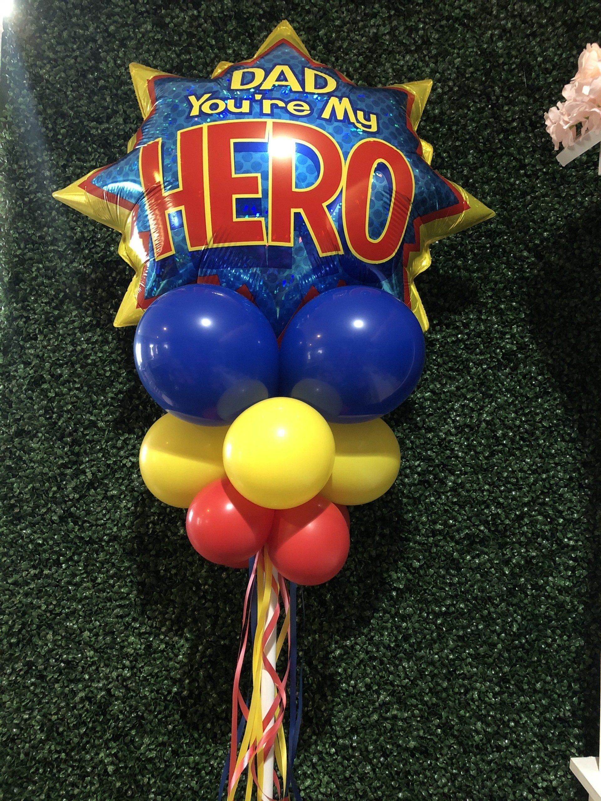 Dad you’re my hero star-shaped Father’s Day foil balloon with blue balloon base on greenery backdrop