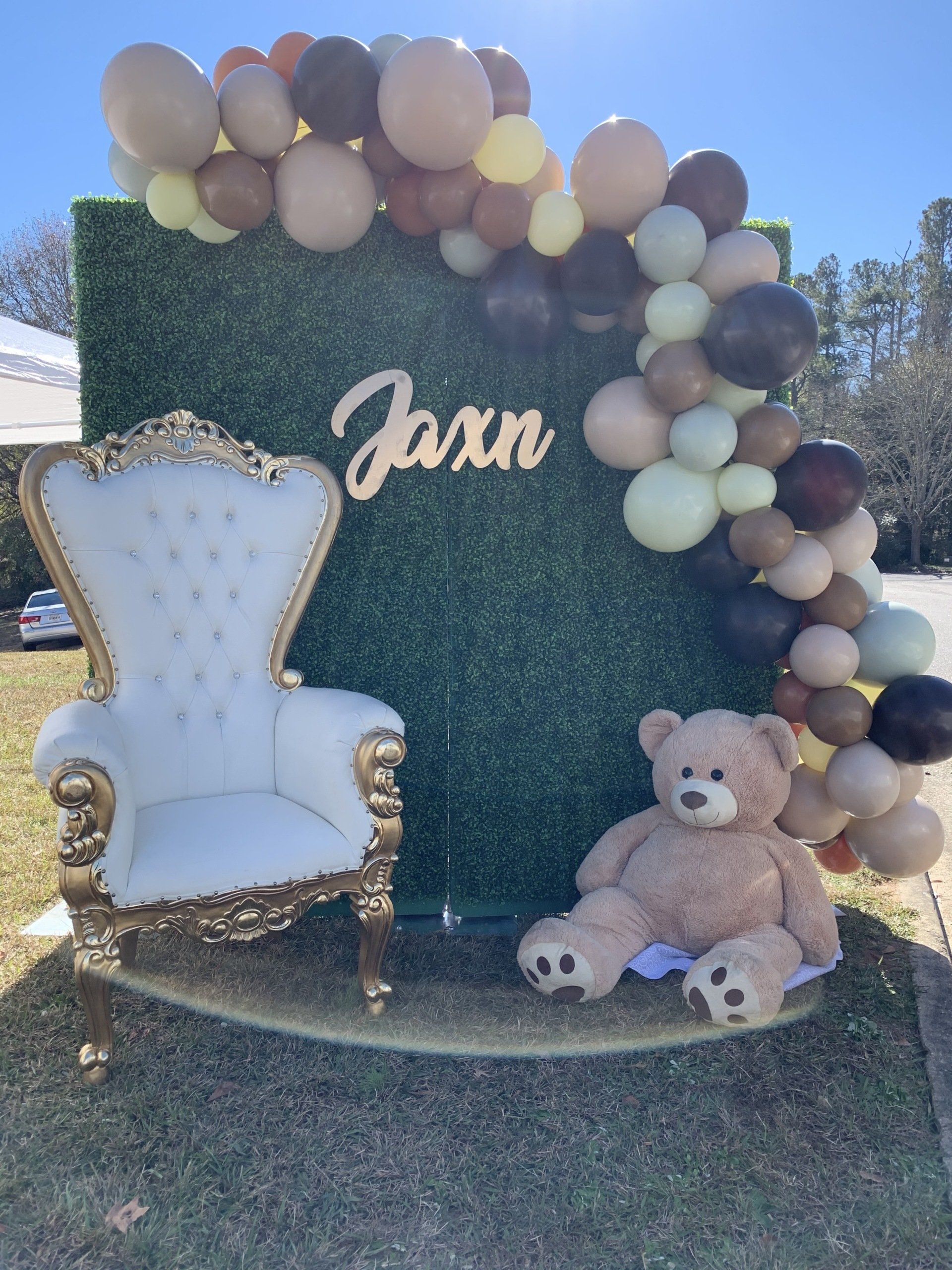 Neutral taupe and cream balloon garland on hedge wall backdrop with custom name sign for baby shower