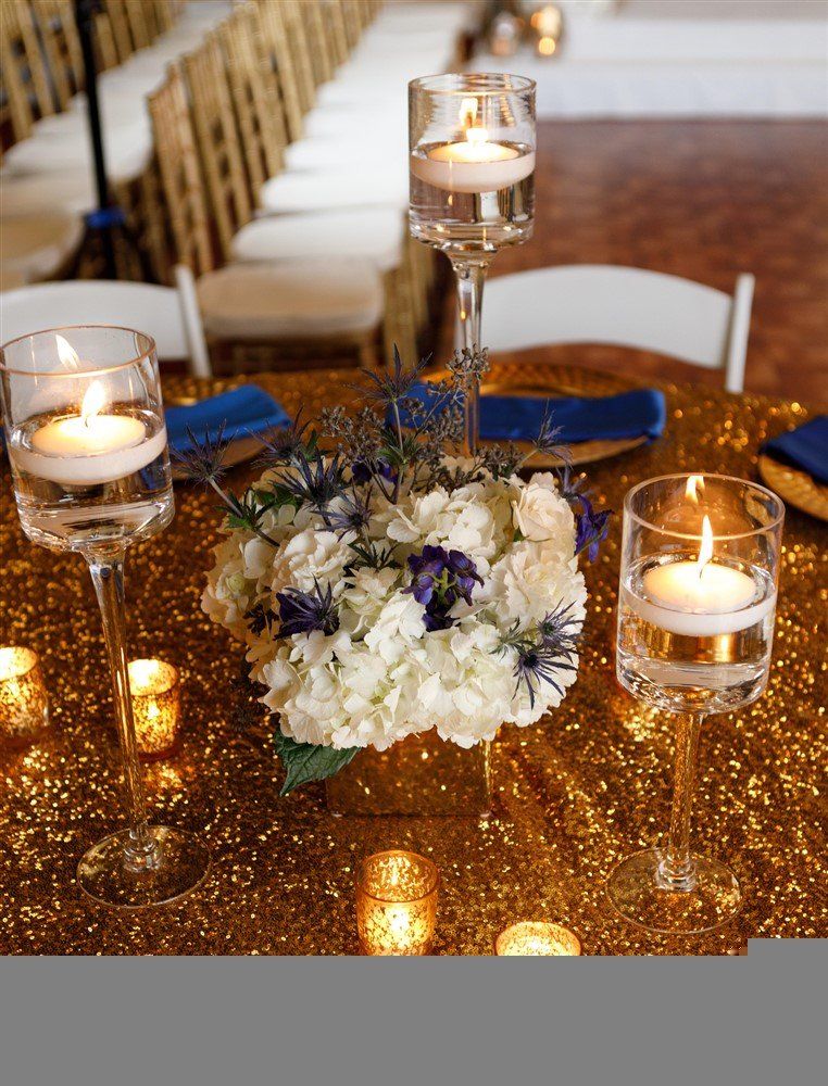 Glass candle holders and floral table décor arranged along a formal reception table