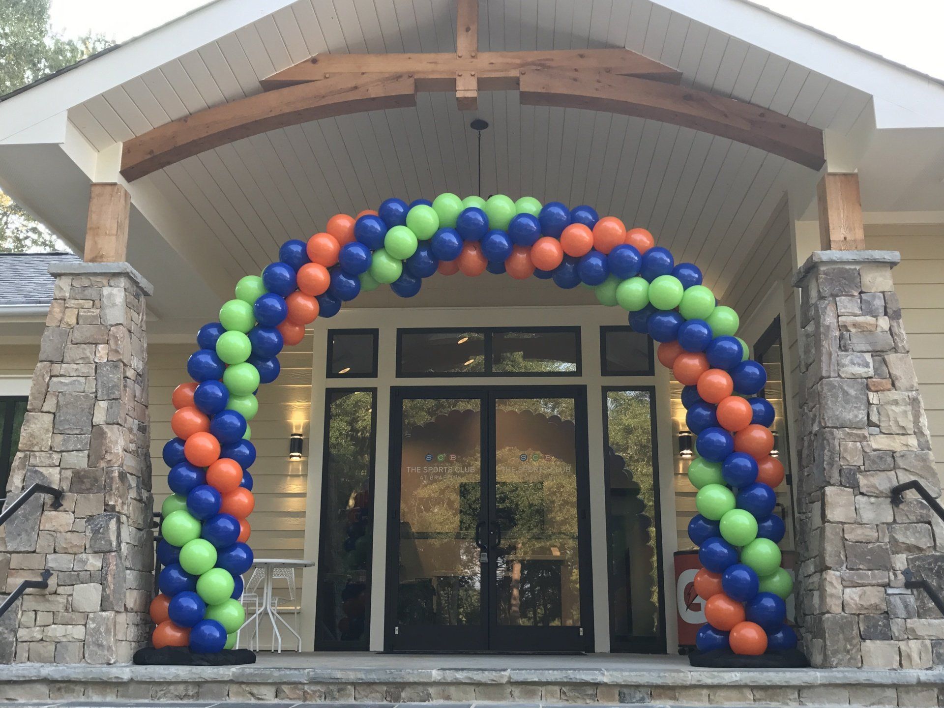 A traditional arch created with spiraling orange, blue and green balloons.
