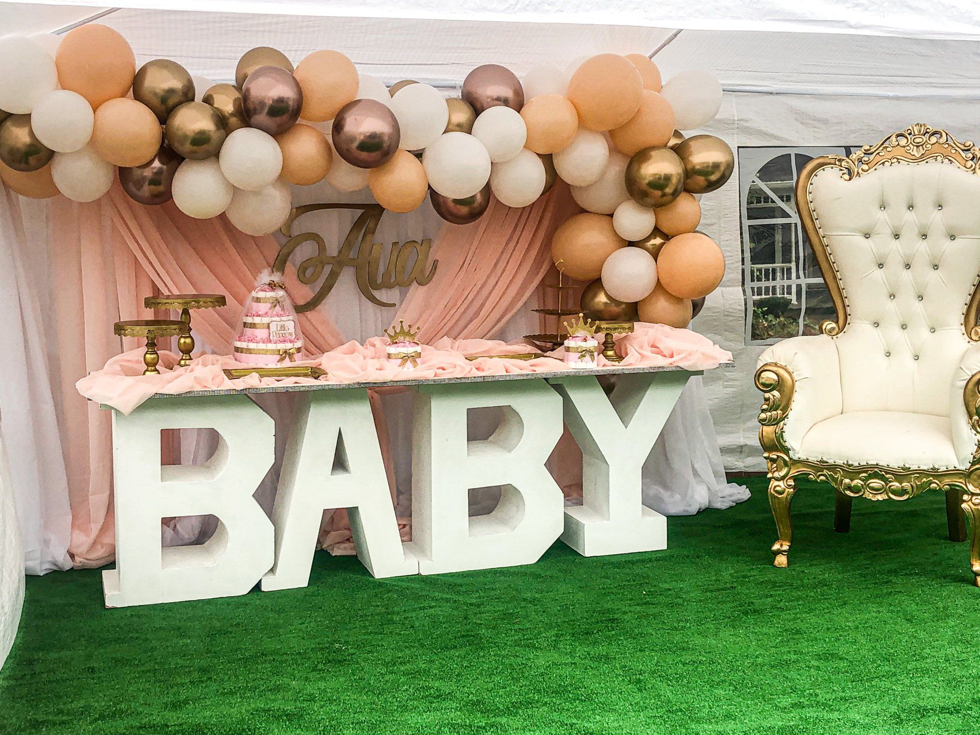 Blush and gold baby shower backdrop with organic balloon garland BABY marquee letters and throne chair