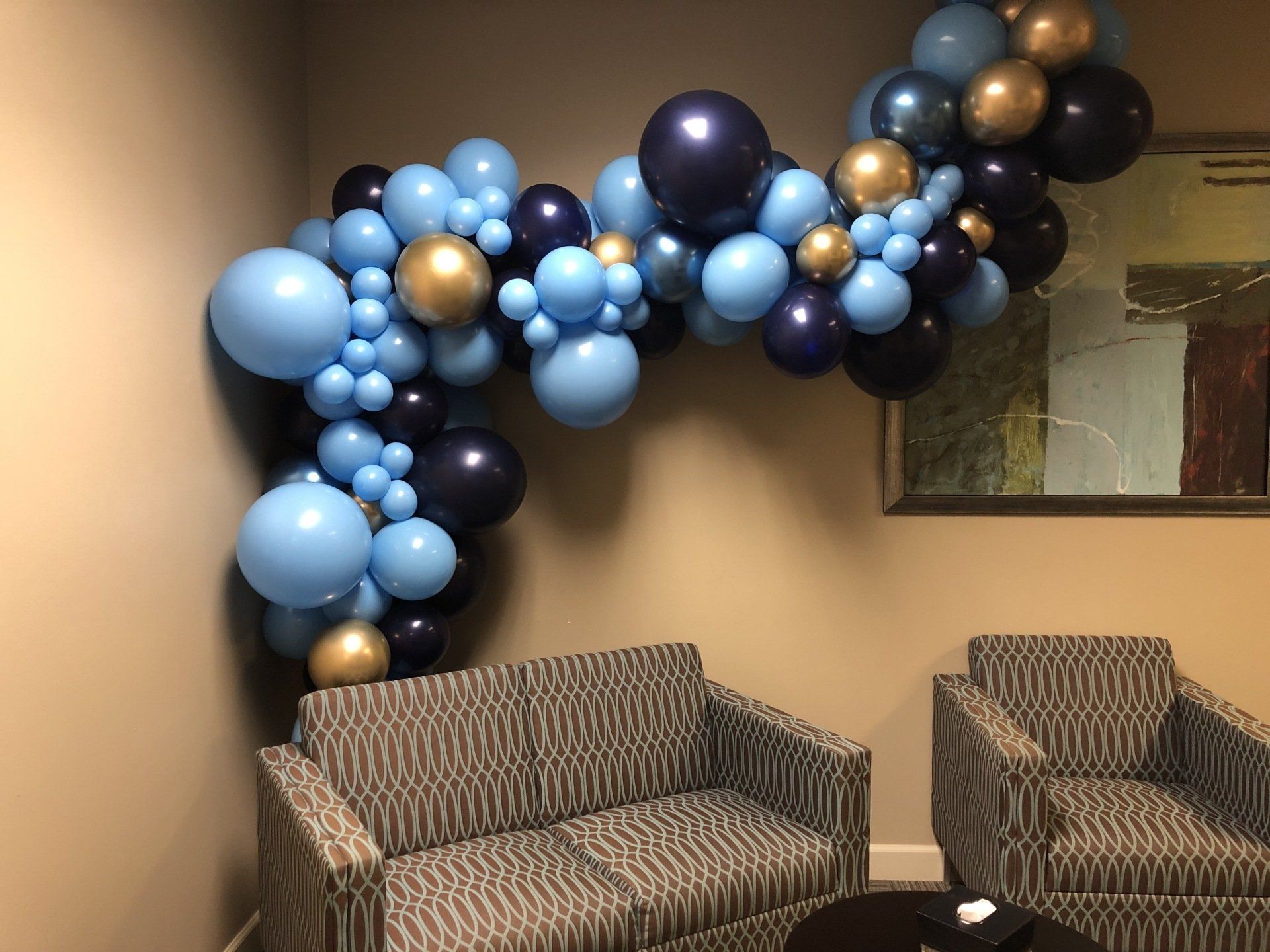 Blue navy and gold organic balloon garland styled above lounge seating for indoor celebration