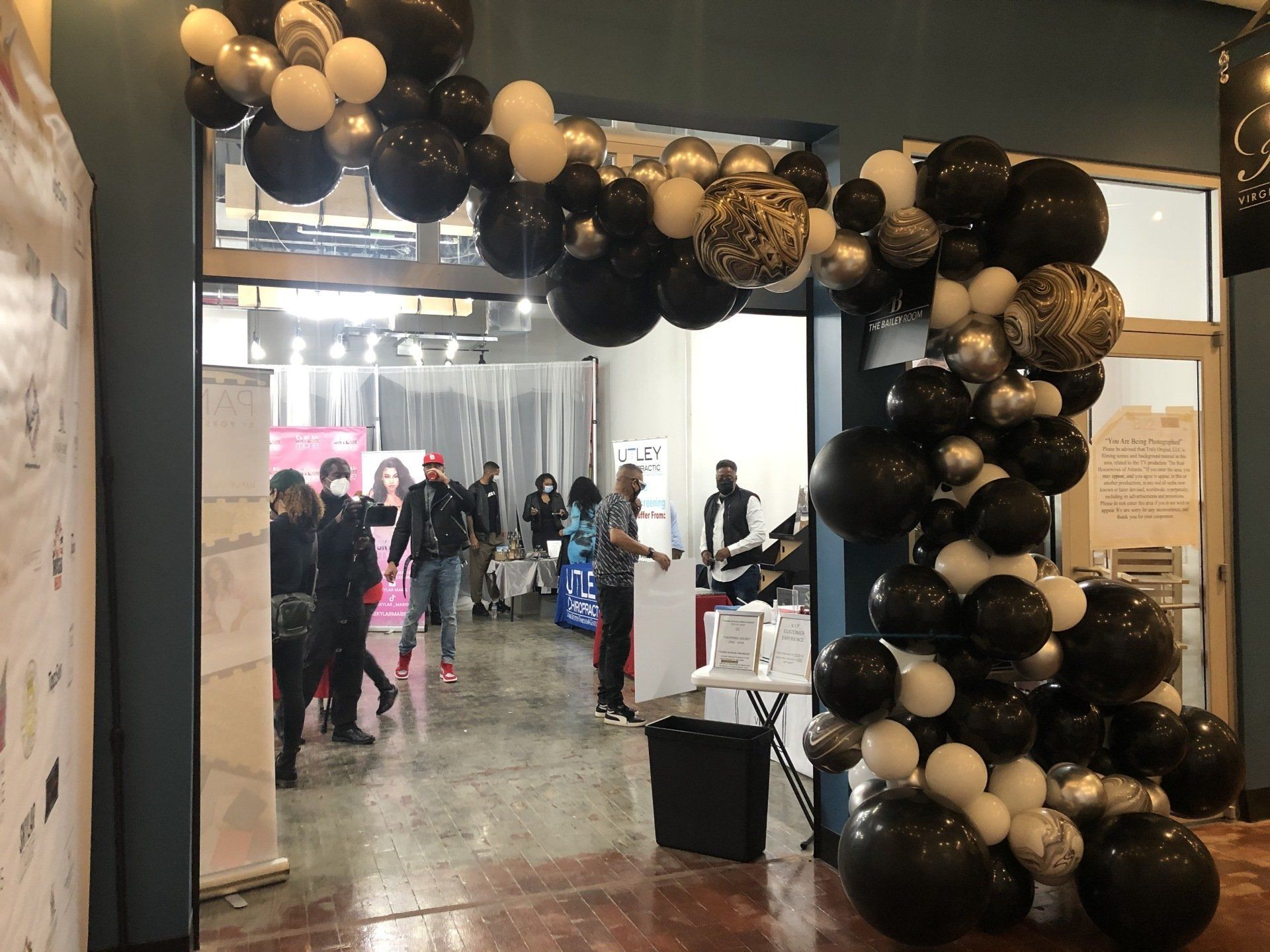 Black and gold balloon arch framing indoor venue entrance for upscale event or grand opening