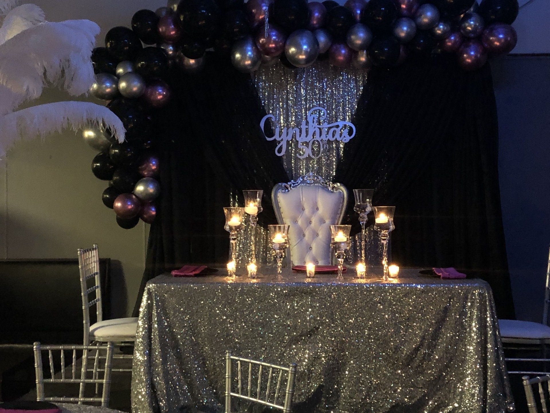Black and gold luxury balloon backdrop with throne chair candles and sequin table for formal celebration