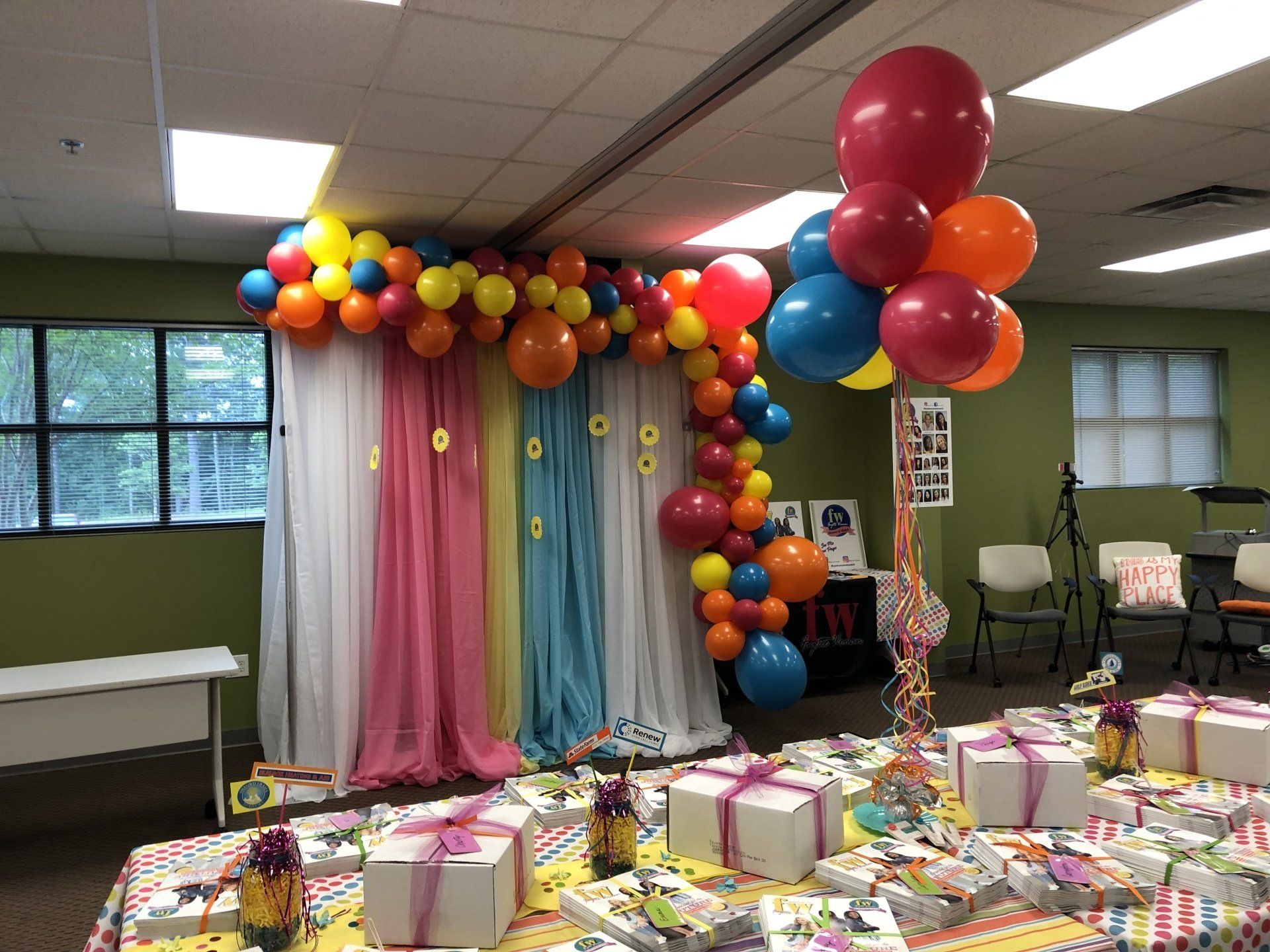 Rainbow balloon garland with colorful drapes and large balloon cluster for kids birthday party setup