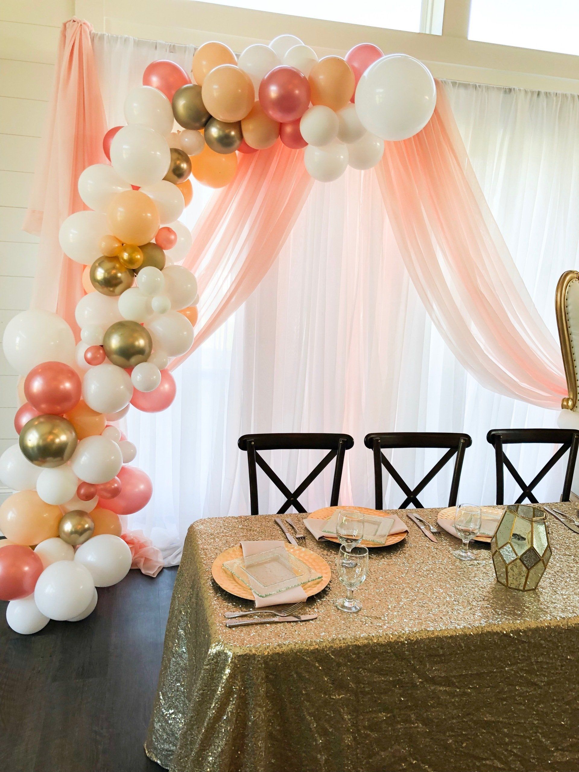 Peach white and gold balloon arch with soft draped backdrop for elegant baby shower