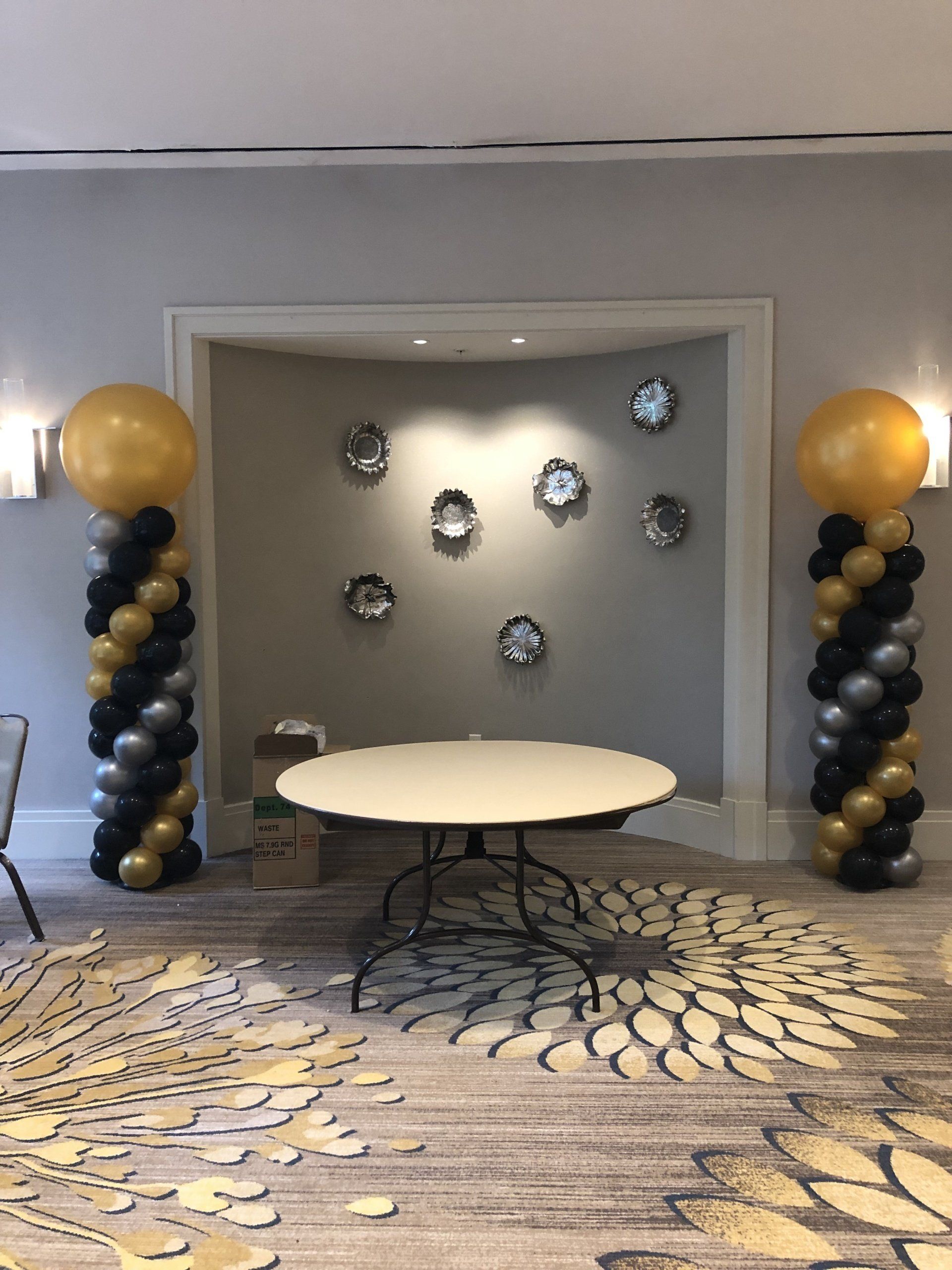 Black and gold balloon columns decorating a modern indoor hallway entrance