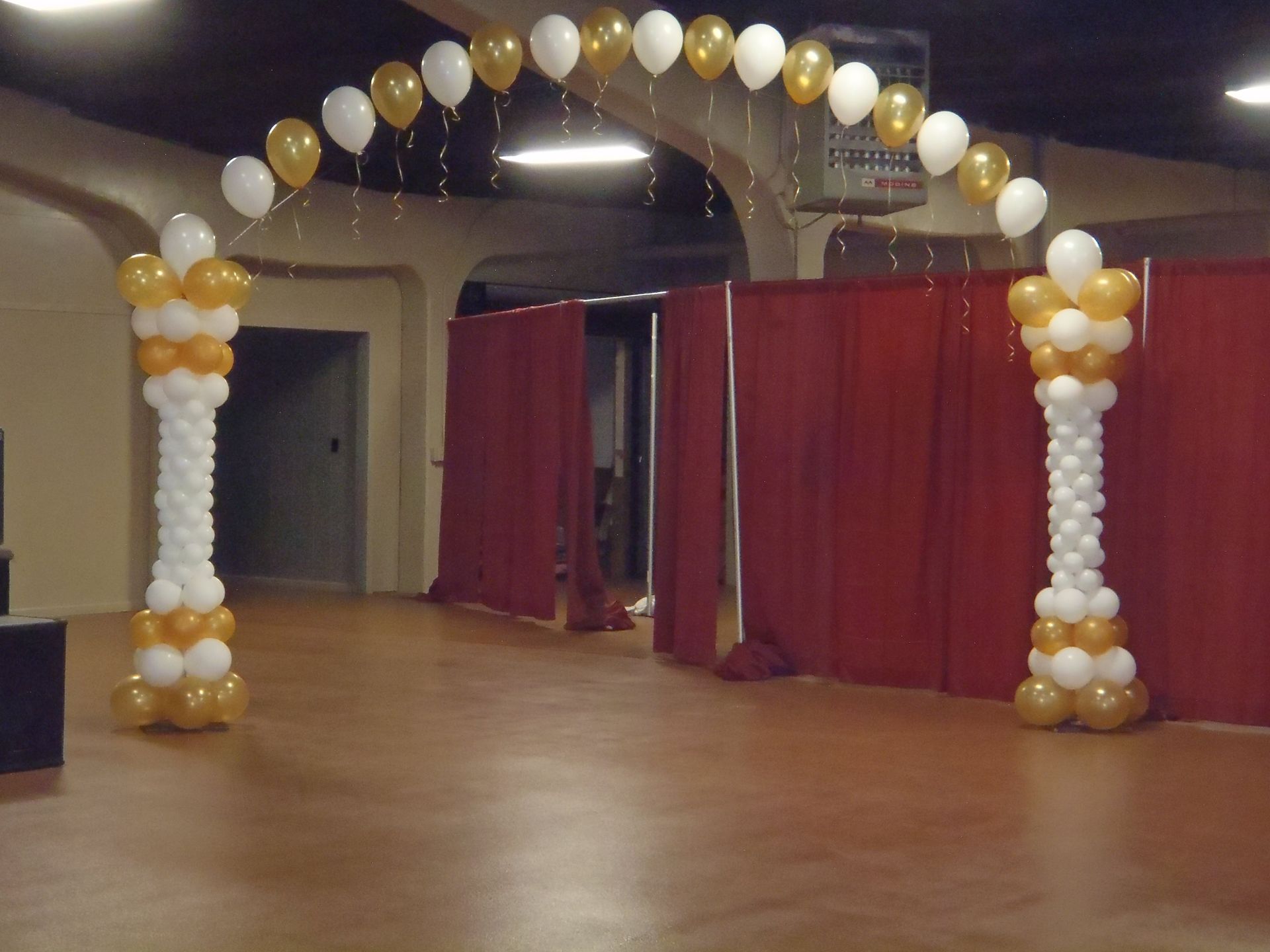 A welcoming balloon archway with white and gold balloons.