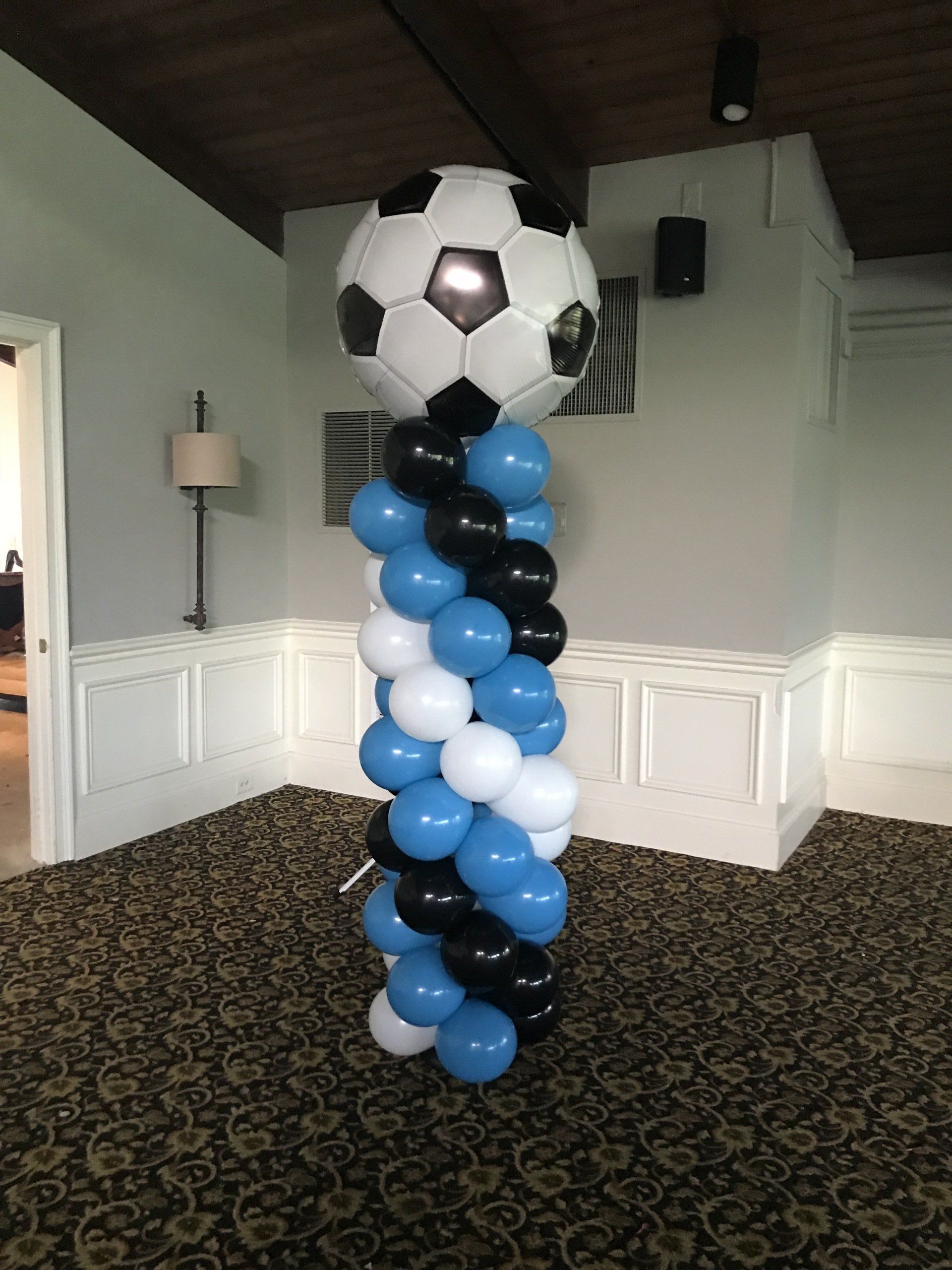 Soccer ball themed balloon column with black and white topper for a sports party setup
