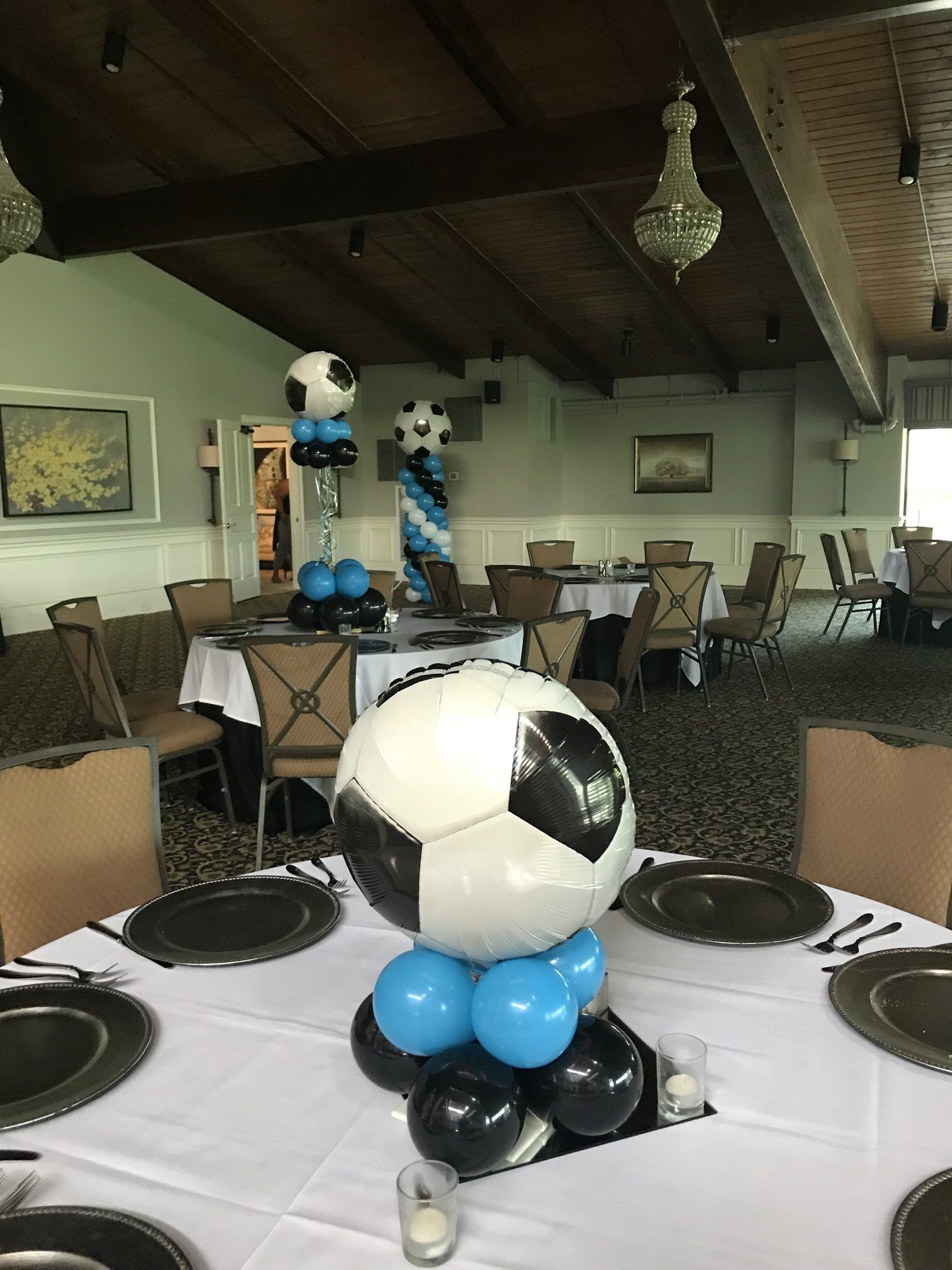 Soccer ball themed balloon columns set up around tables inside an event venue