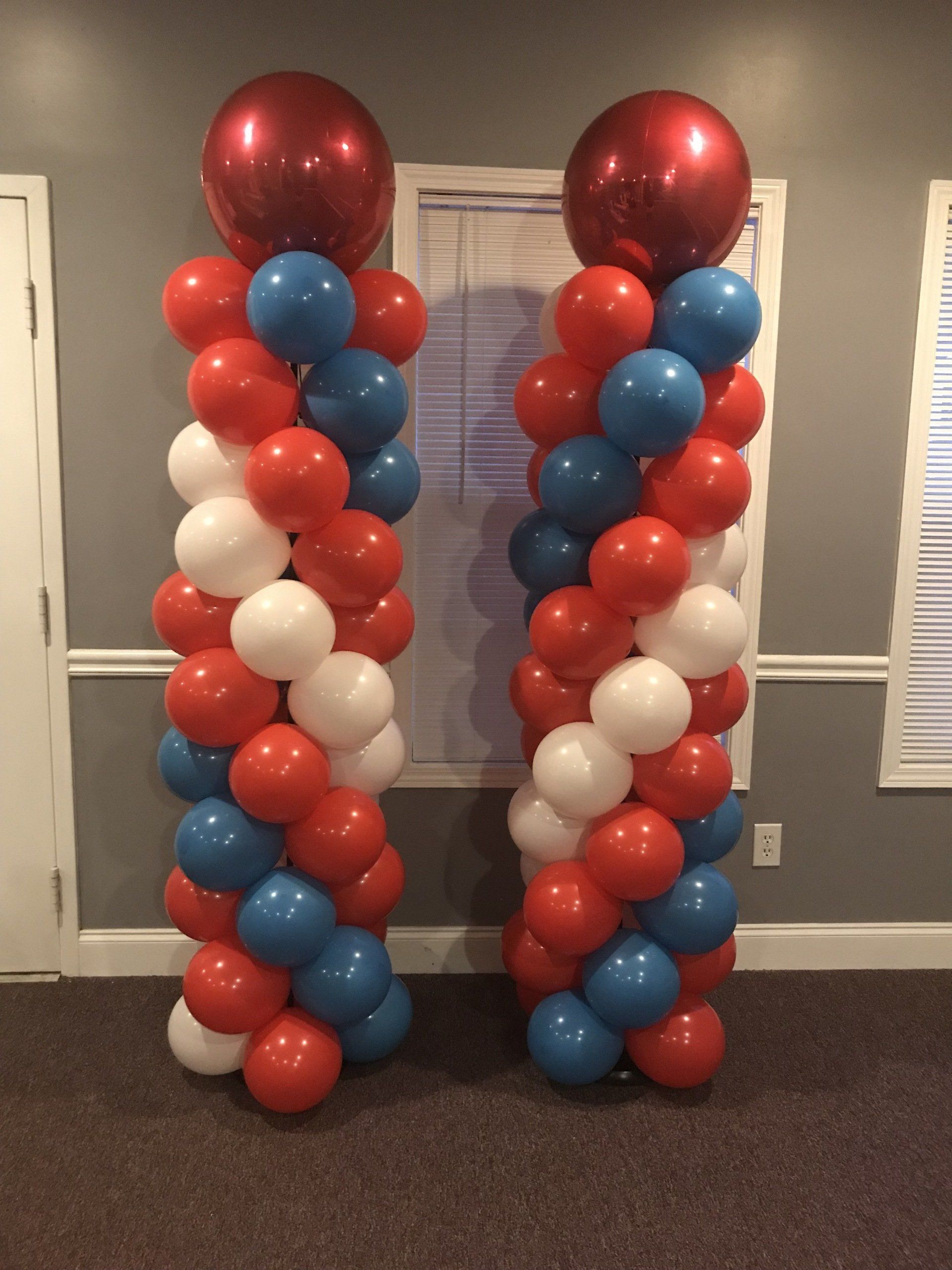 Red, white, and blue balloon columns with large metallic red topper balloons for an indoor celebration