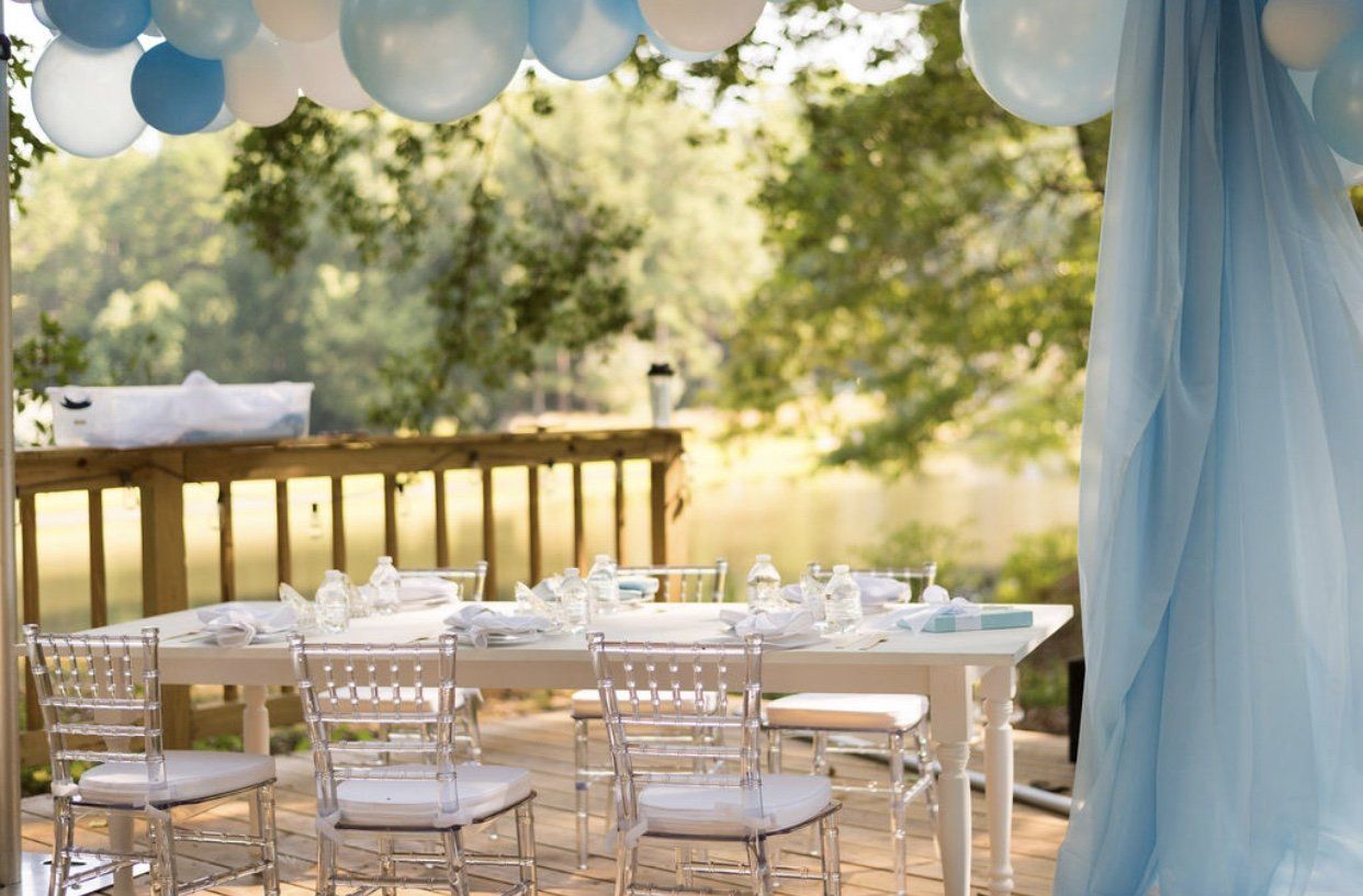 Outdoor canopy dining area with white chairs and soft blue draping for kids party or family event reception