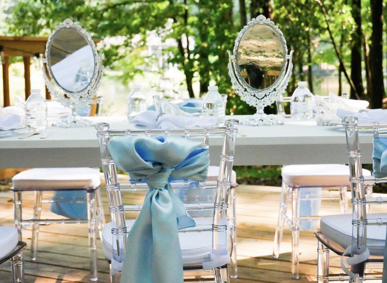 Kids party table with blue bows clear chairs and vanity mirror centerpieces