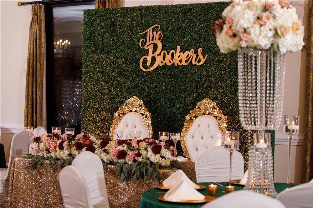 Sweetheart table with floral arrangements and custom boxwood backdrop for wedding décor
