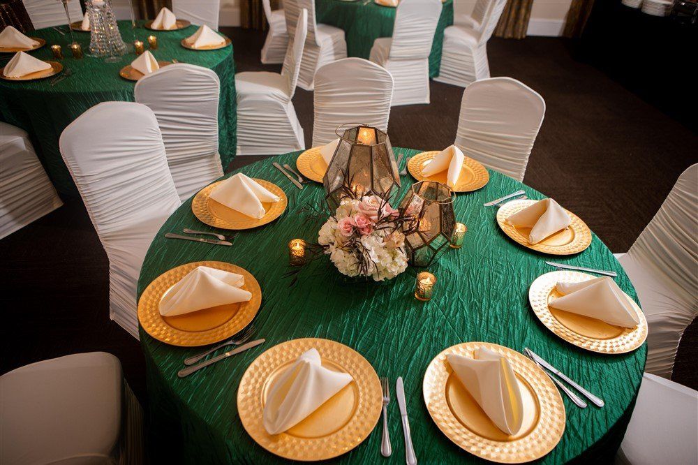 Emerald green table linens with gold chargers and floral centerpieces for formal event