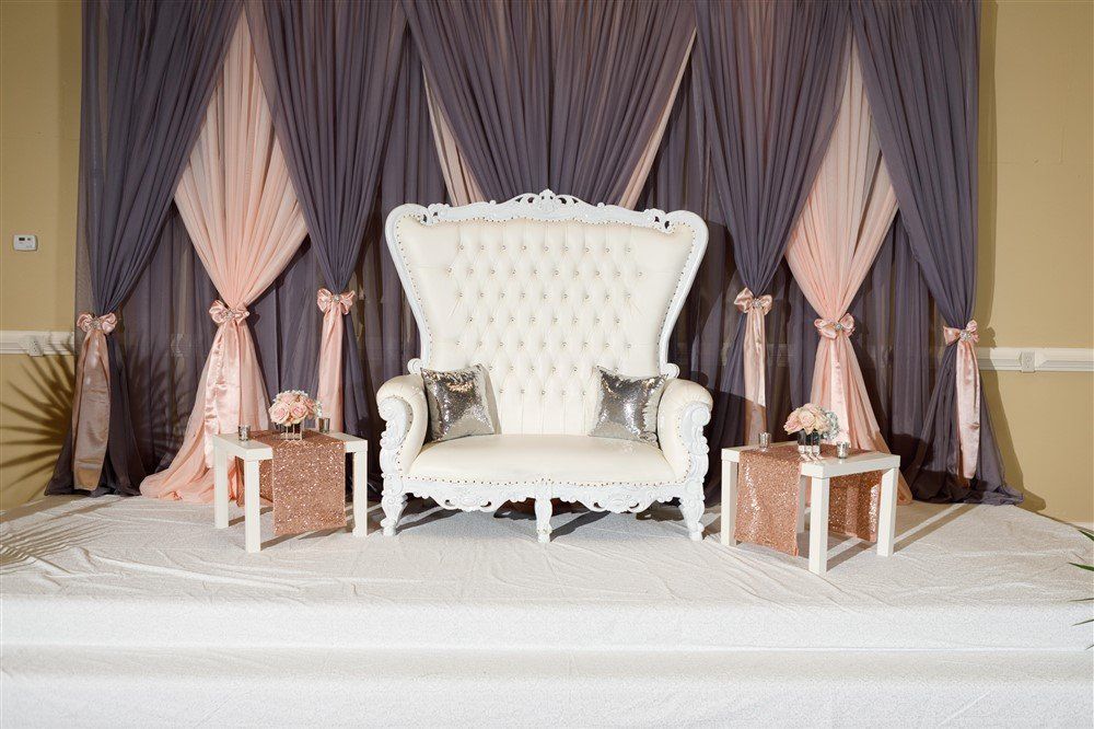 Luxury lounge backdrop with soft mauve draping and white tufted throne chair for bridal shower or elegant celebration seating
