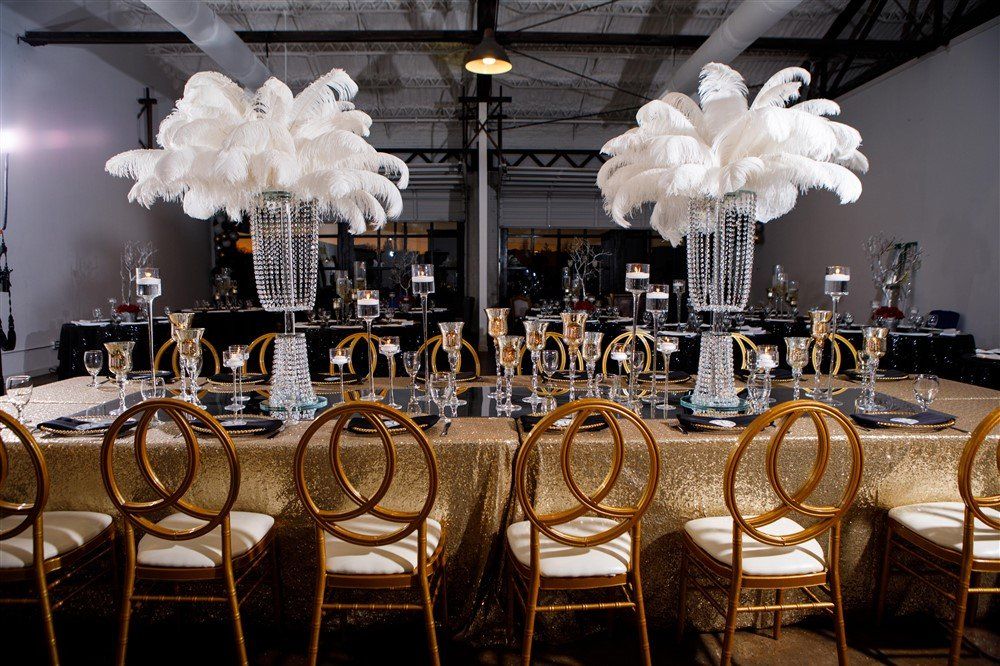 Luxury event tablescape with white feather centerpieces, gold accents, and elegant seating