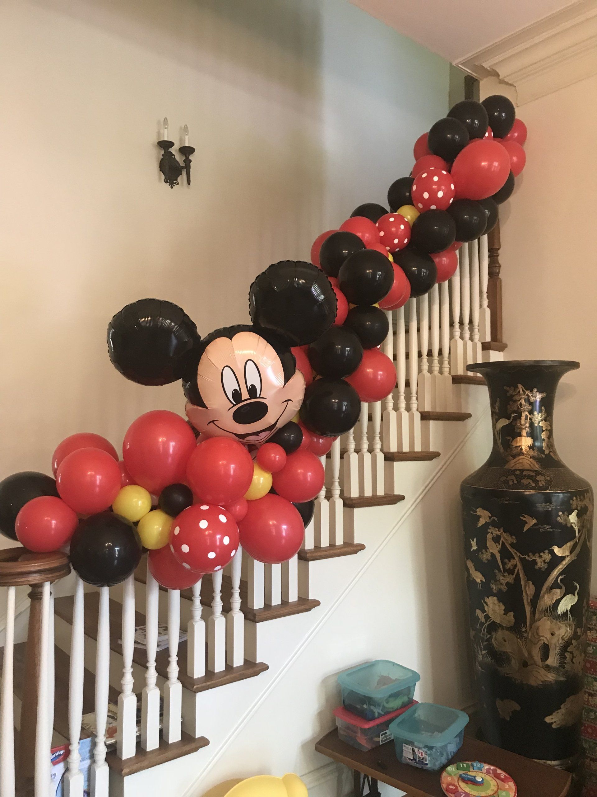 A Micky Mouse themed garland decorates a stair case banister.