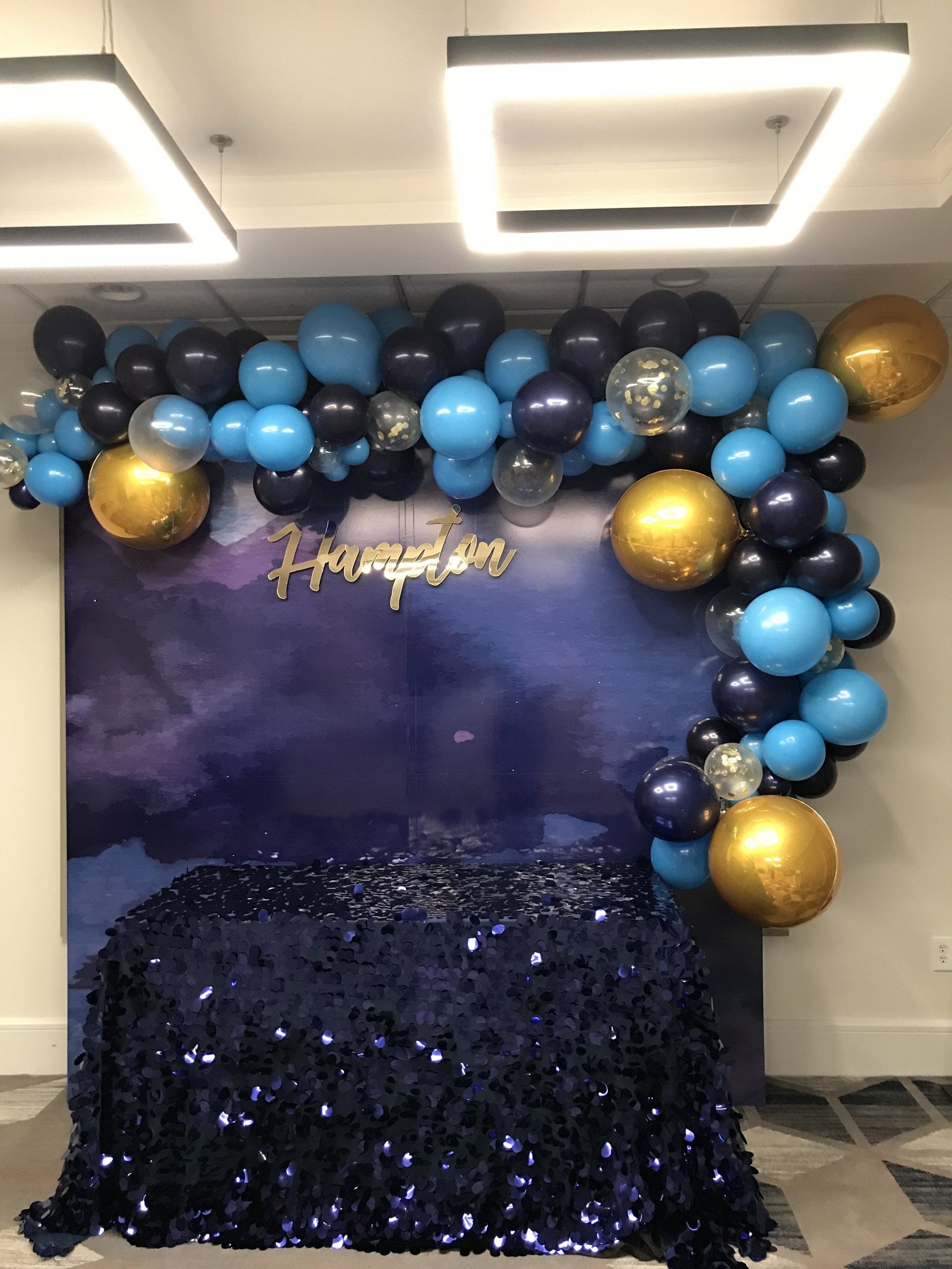 A fancy garland comprised of balloons frames a blue backdrop.