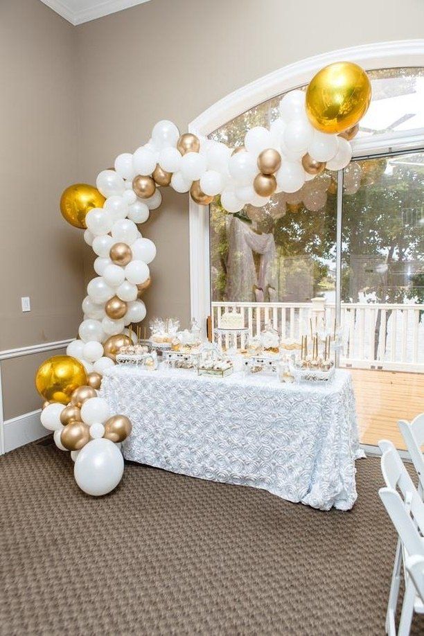 An organic balloon garland frames a dessert table.
