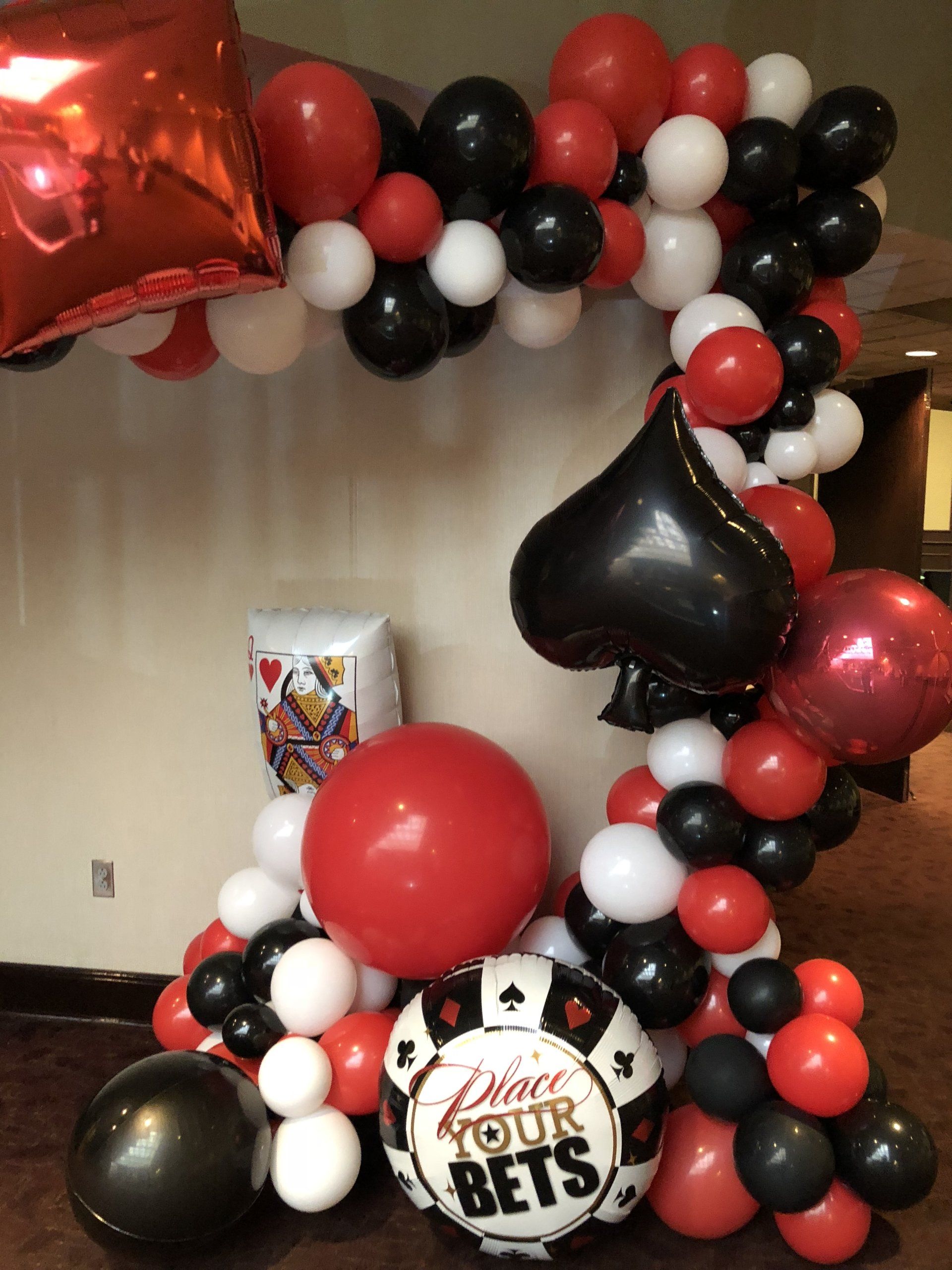 A plying card themed balloon garland comprised of various shapes and colors.