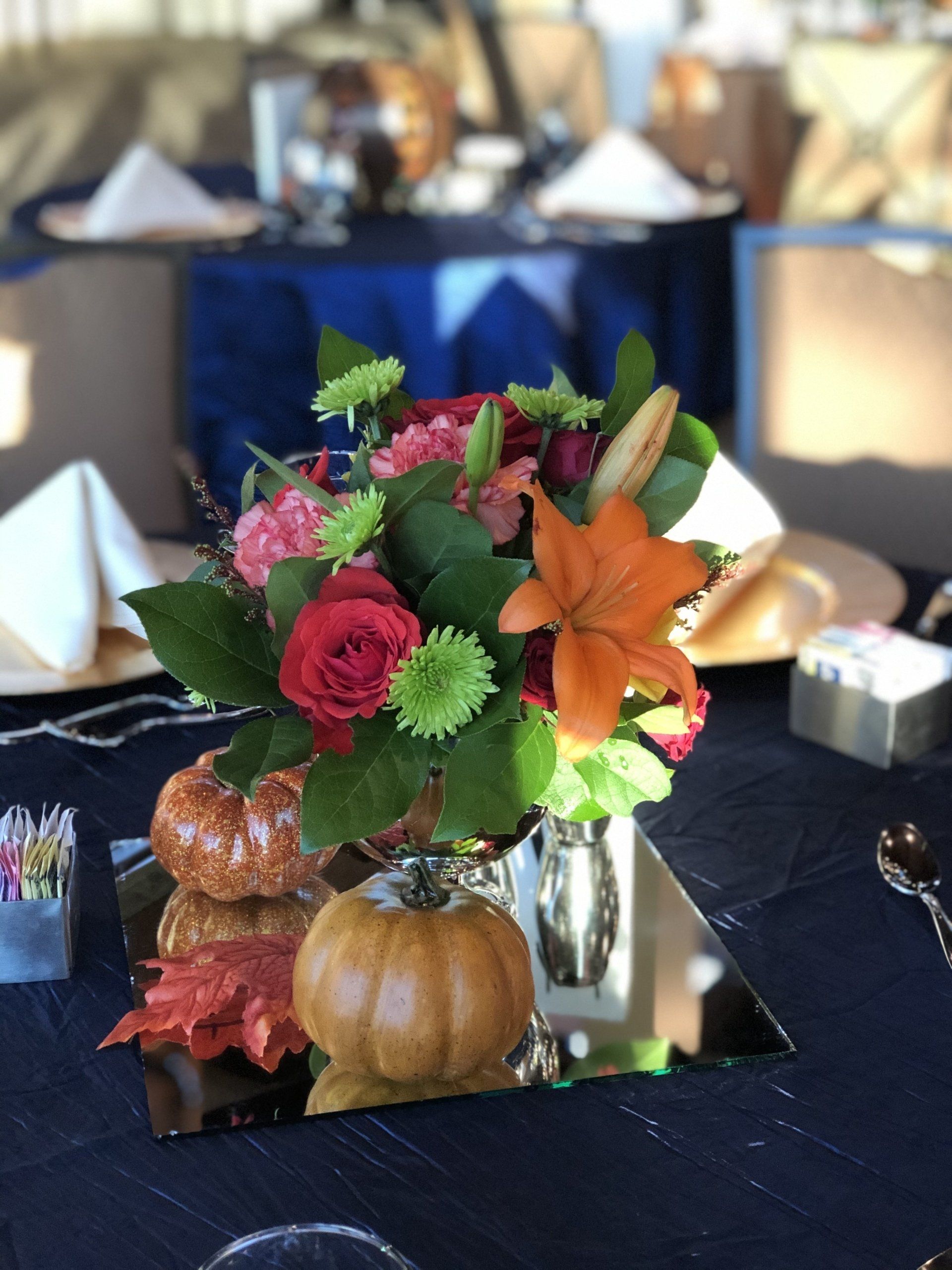 Colorful floral centerpiece with lilies and greenery on a navy blue and gold table setting