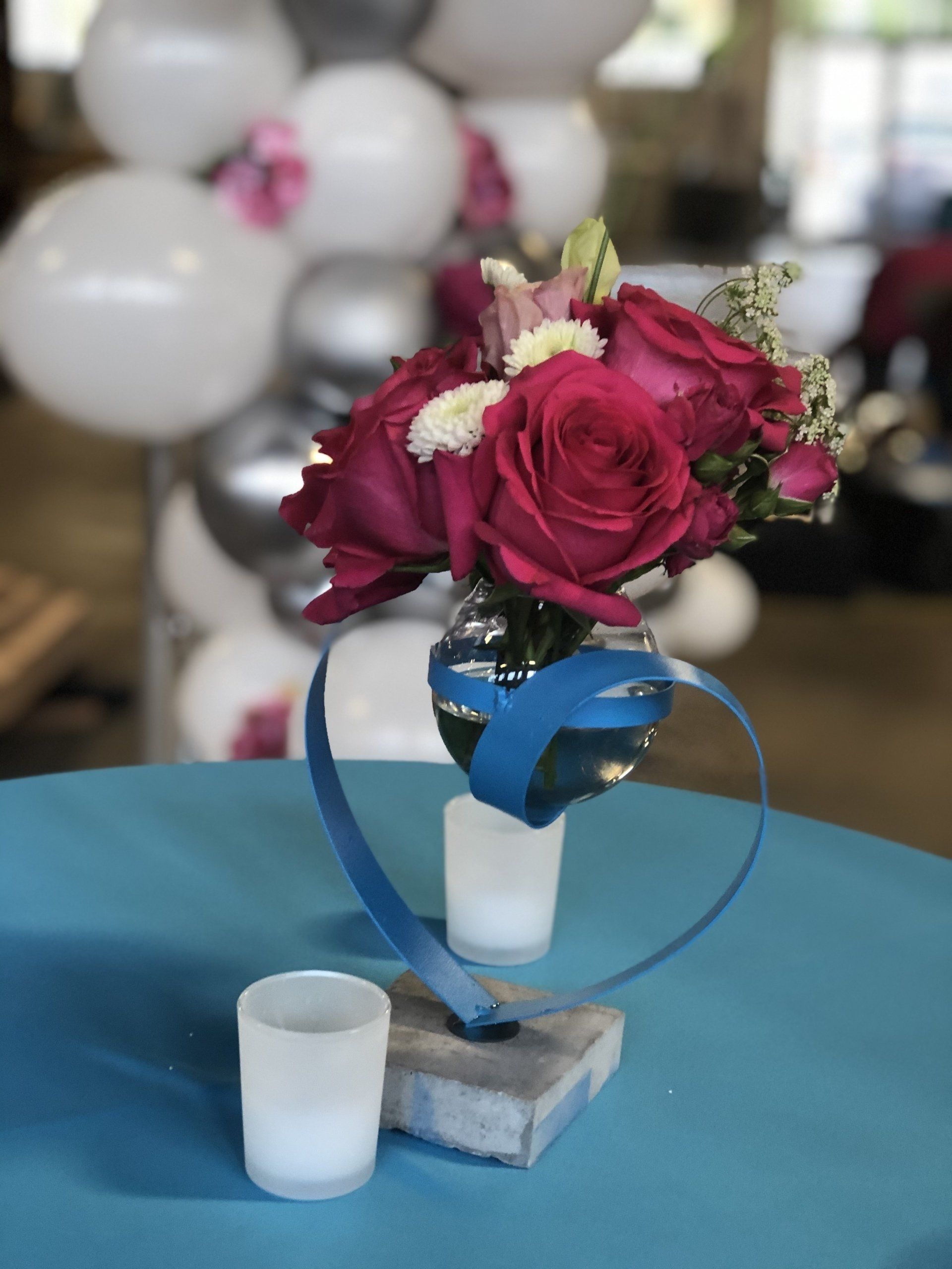 Close-up of burgundy rose bouquet with white balloons blurred in the background