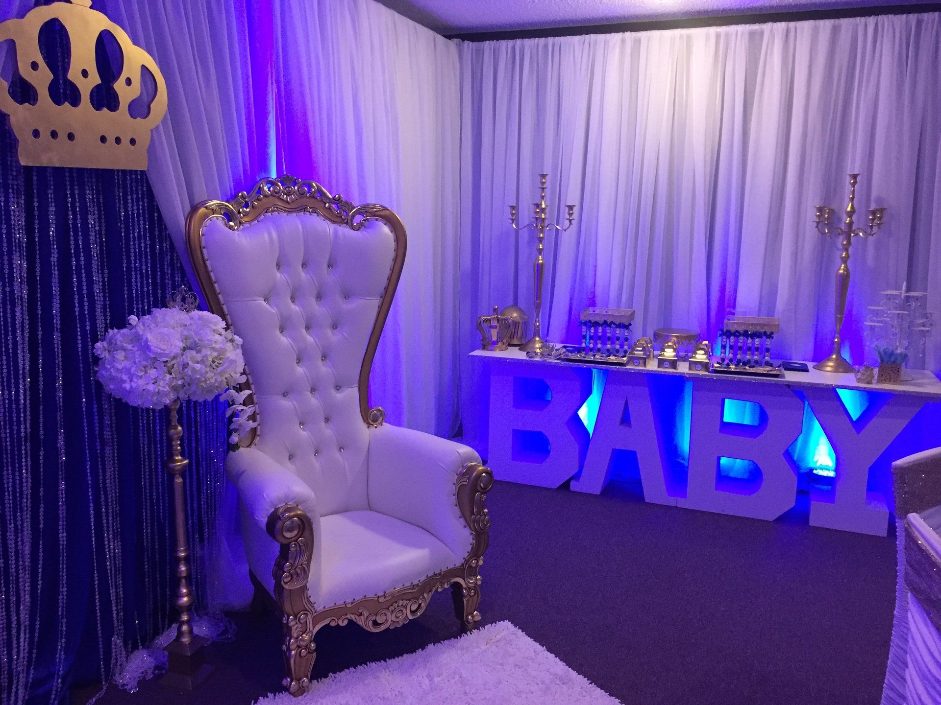 White and gold throne chair with blue BABY marquee letters and elegant draped backdrop