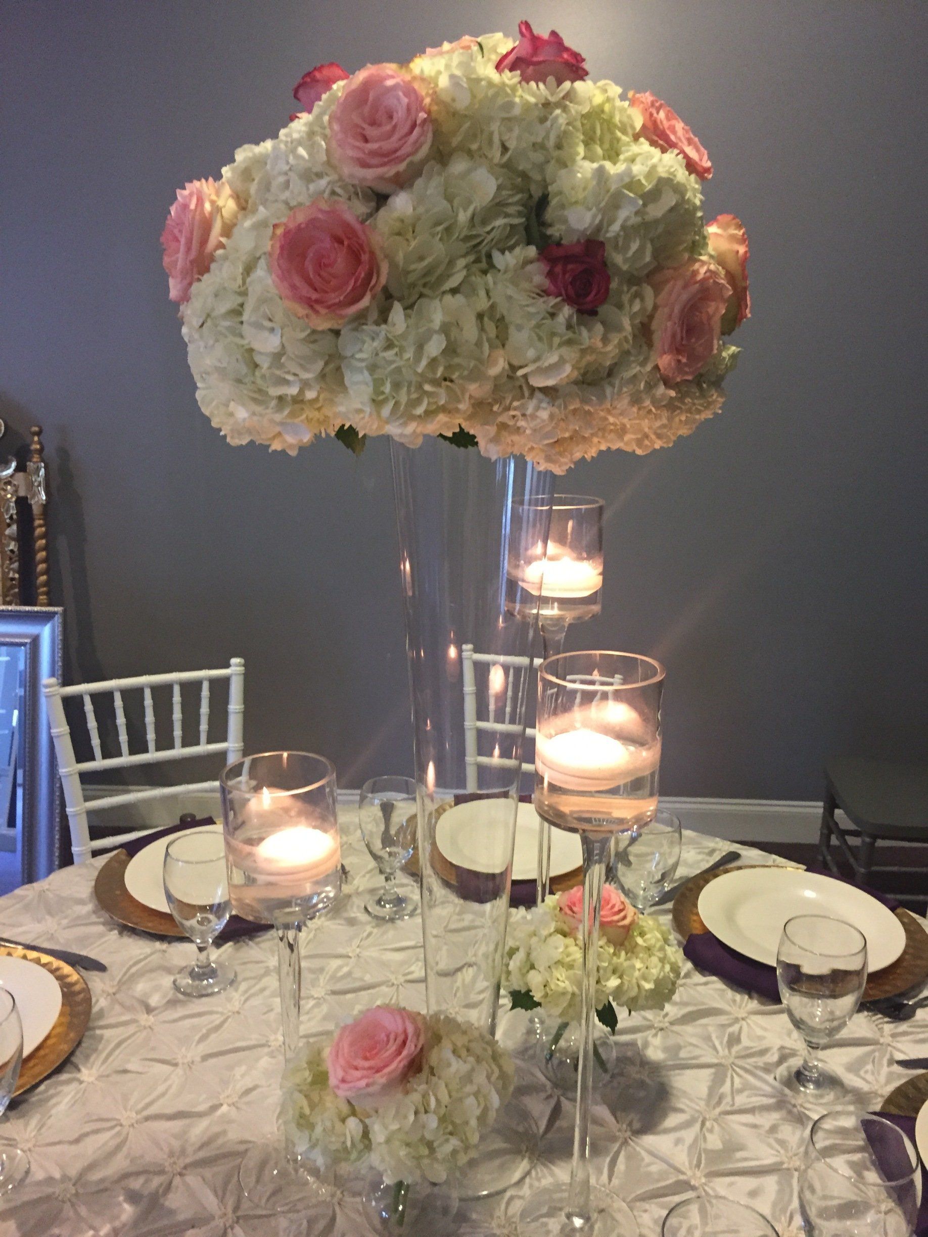Elegant centerpiece design with a tall glass tapered cylinder with floral arrangement 