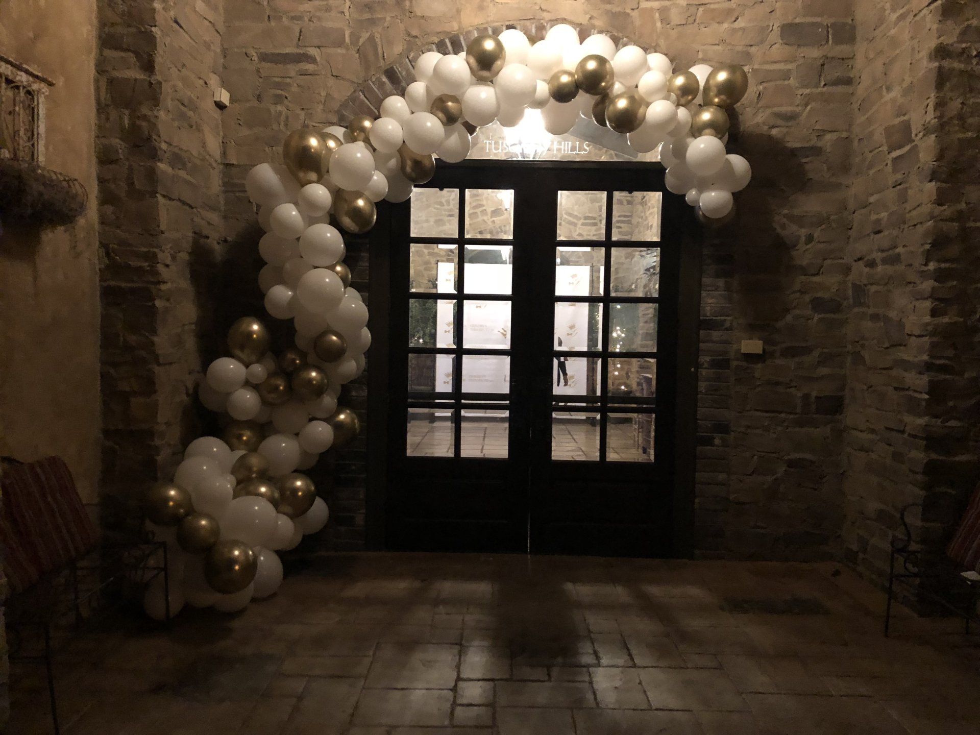 A classy white and gold balloon garland adorn an entrance way.