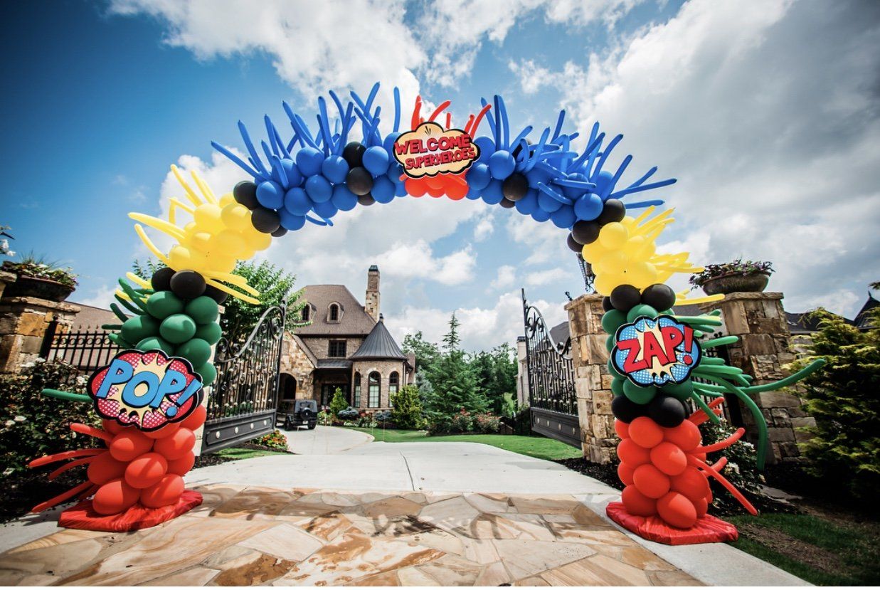 A festive archway with multiple colors and shapes of balloons with a welcome sign at the top.