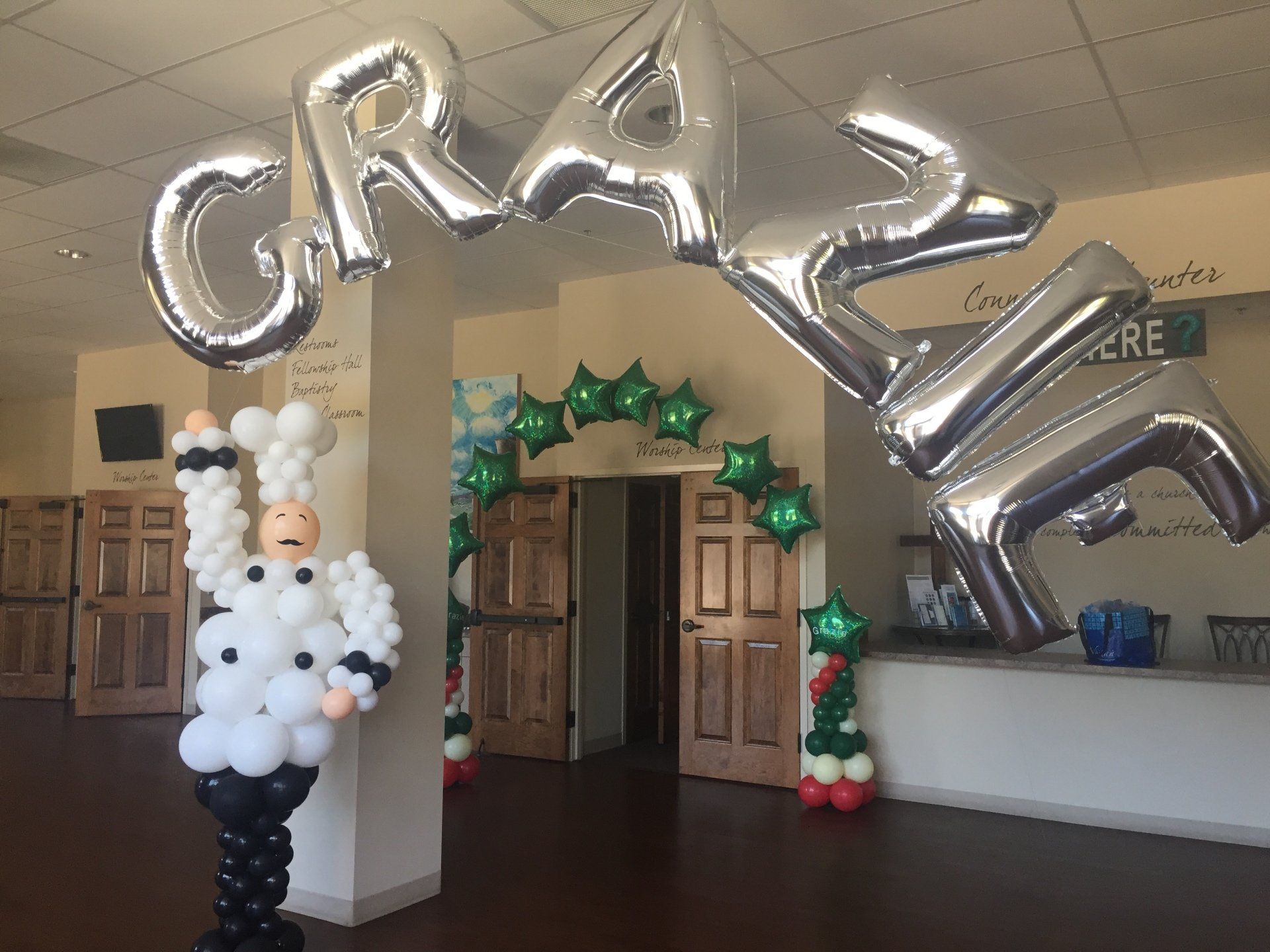 A balloon column that looks like a chef, a balloon lettered archway and a star balloon archway in the background.
