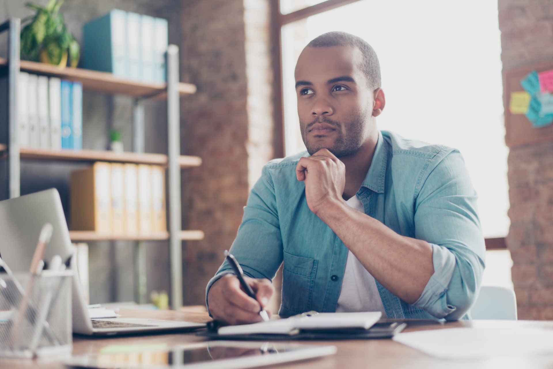 A man is sitting at a desk with a pen in his hand.