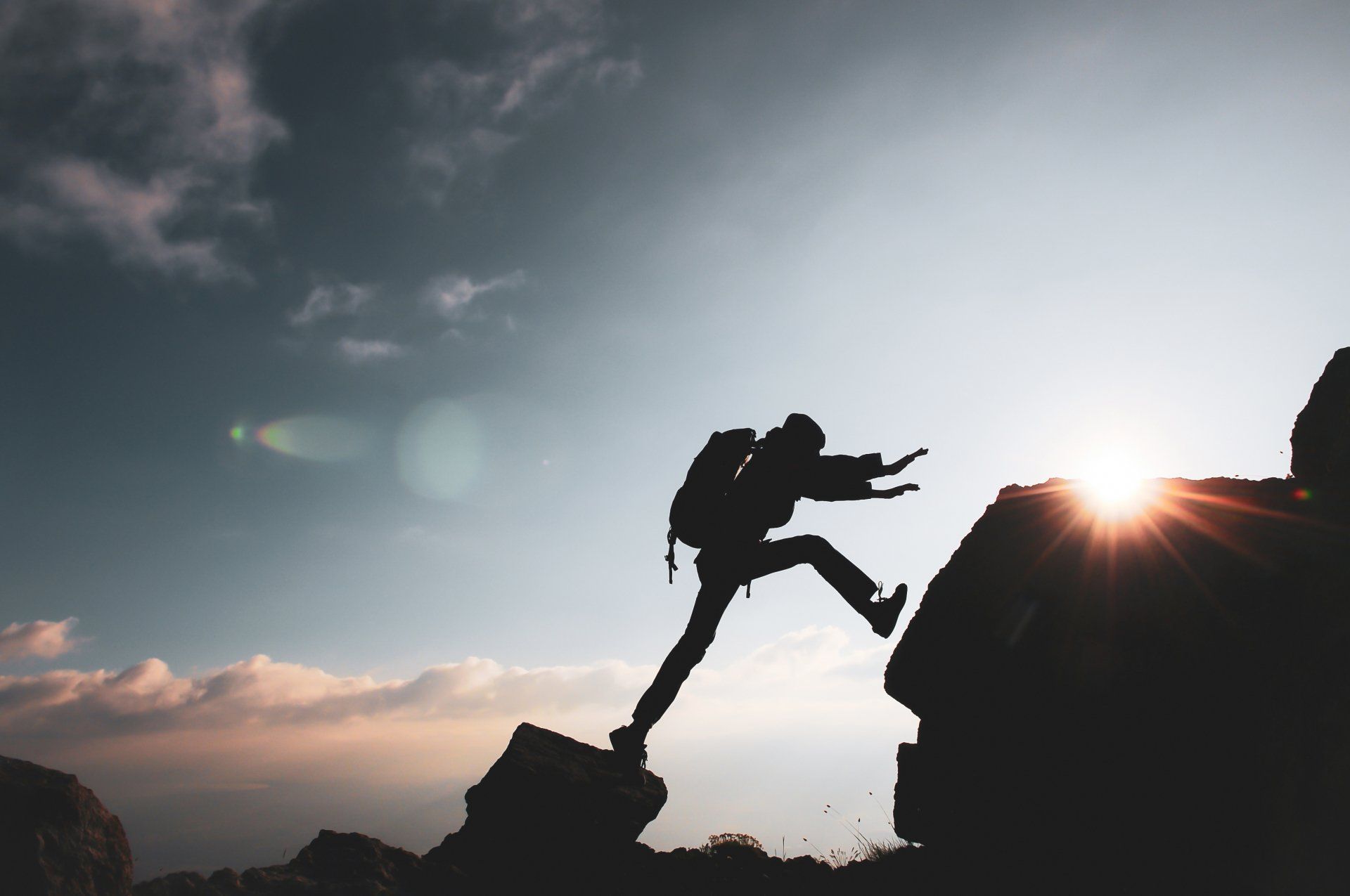 A person with a backpack is climbing a rocky cliff.