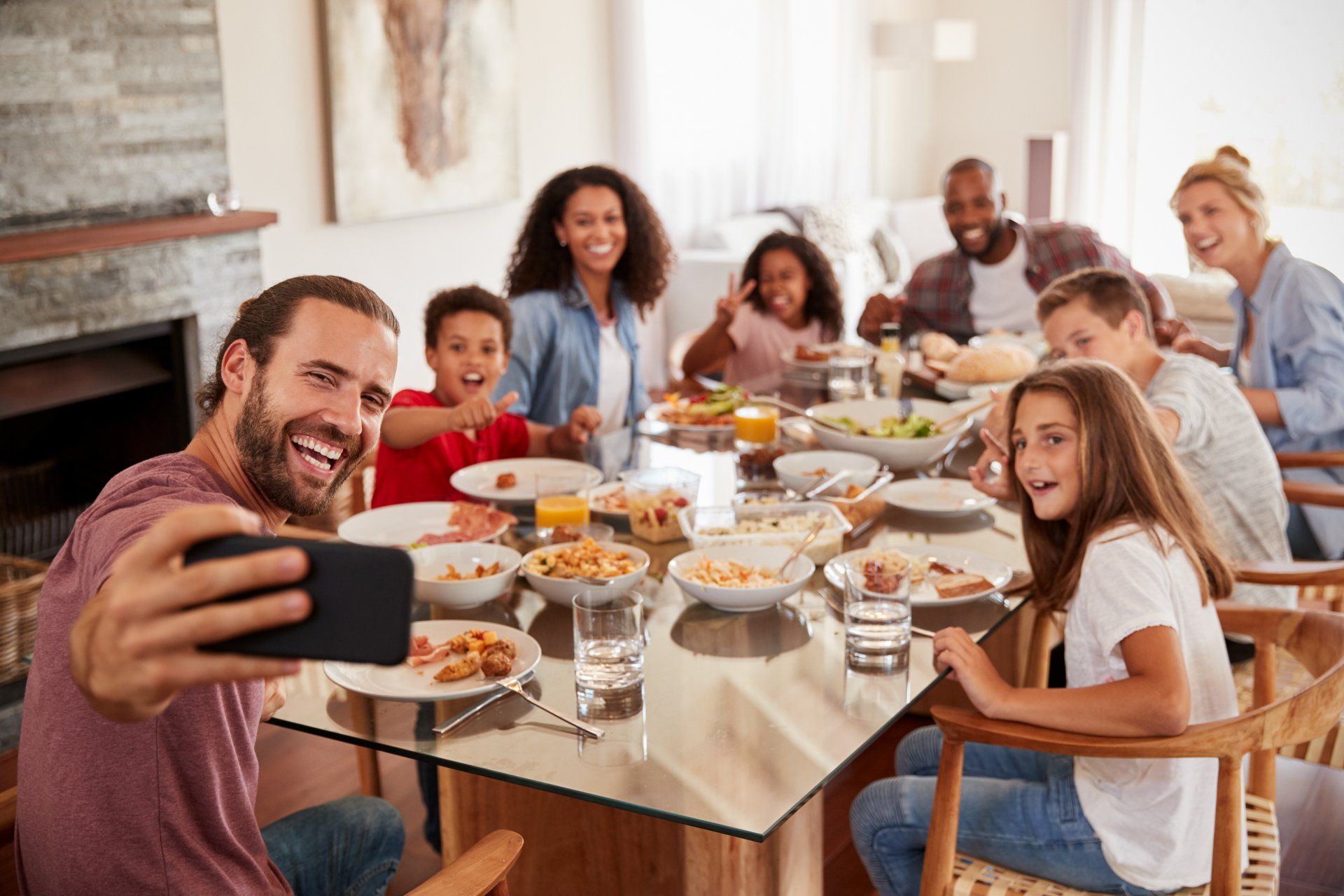 A man is taking a selfie of his family at a dinner table.