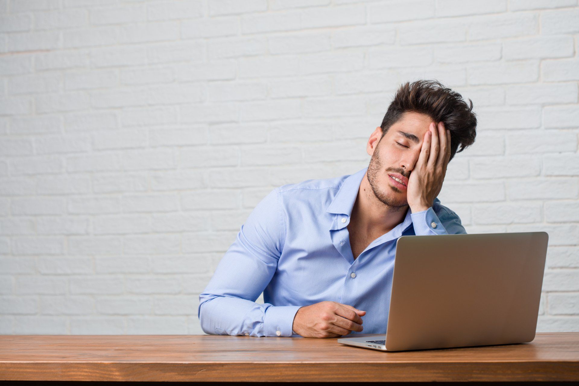 A man is sitting at a desk using a laptop computer.