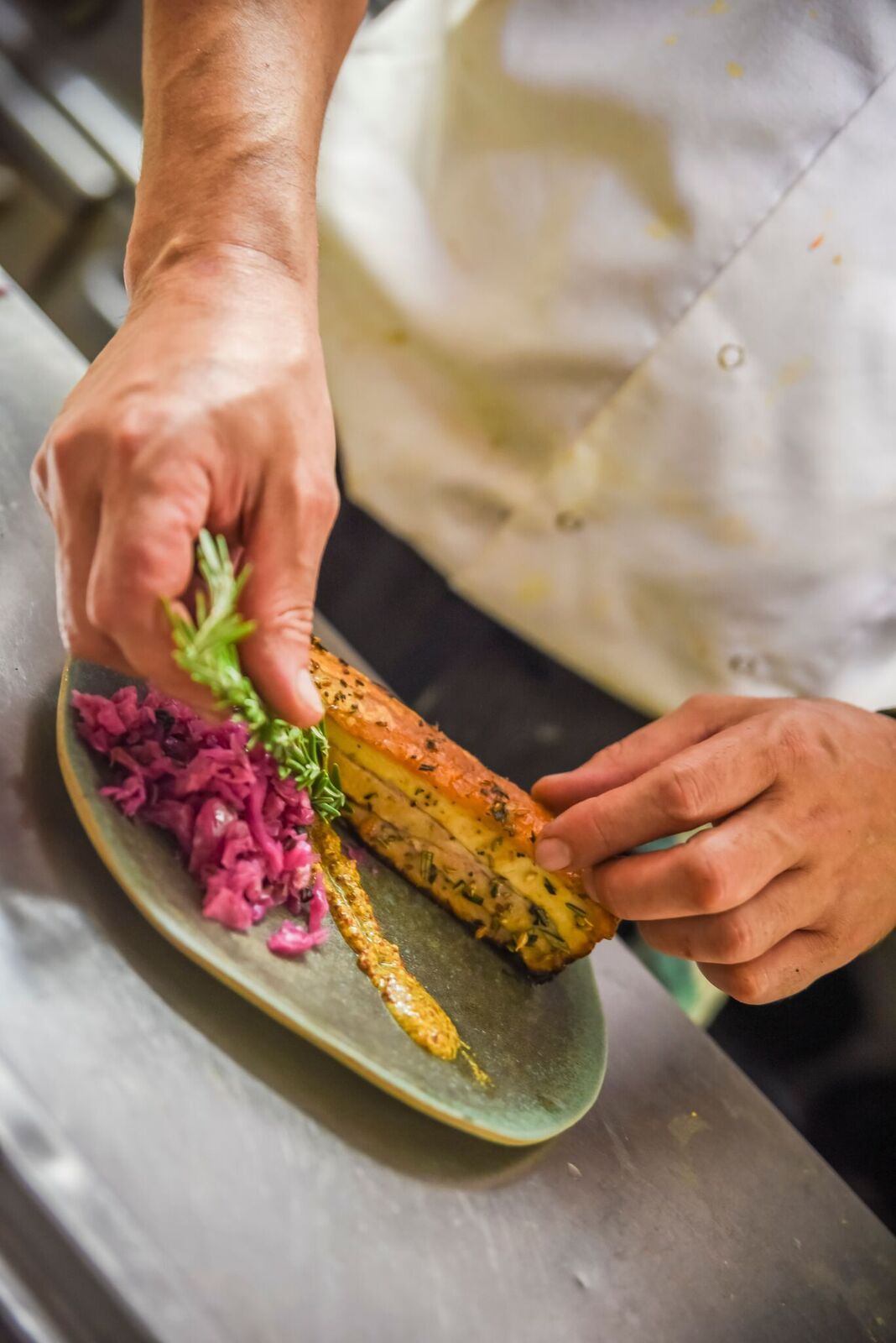 Chef plating colorful vegetables on a green plate in a kitchen