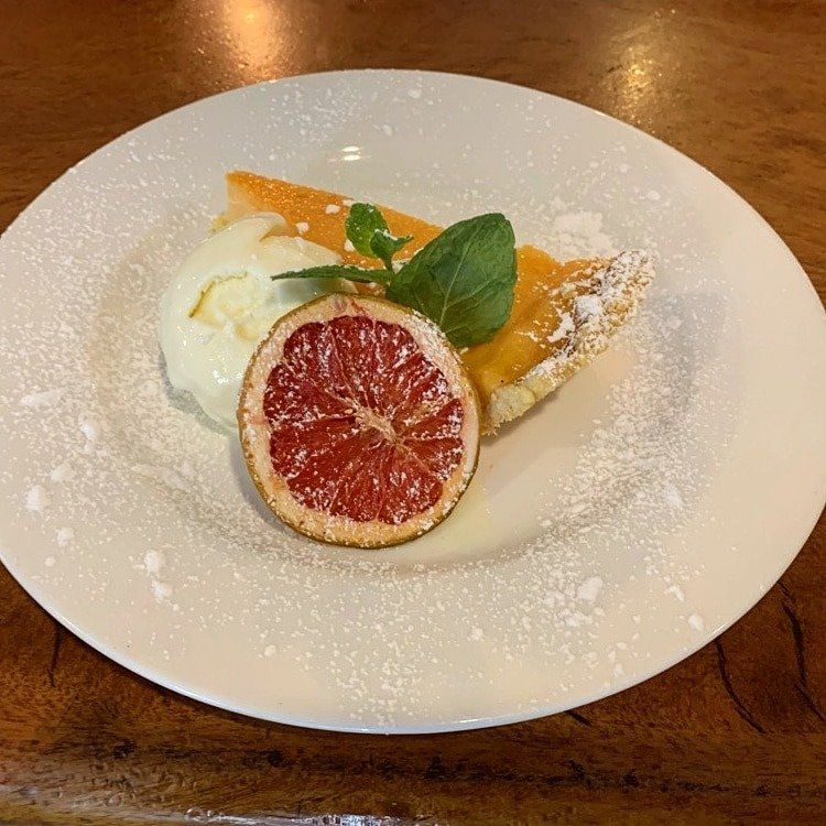 Dessert slice with blood orange and basil on a white plate, dusted with powdered sugar