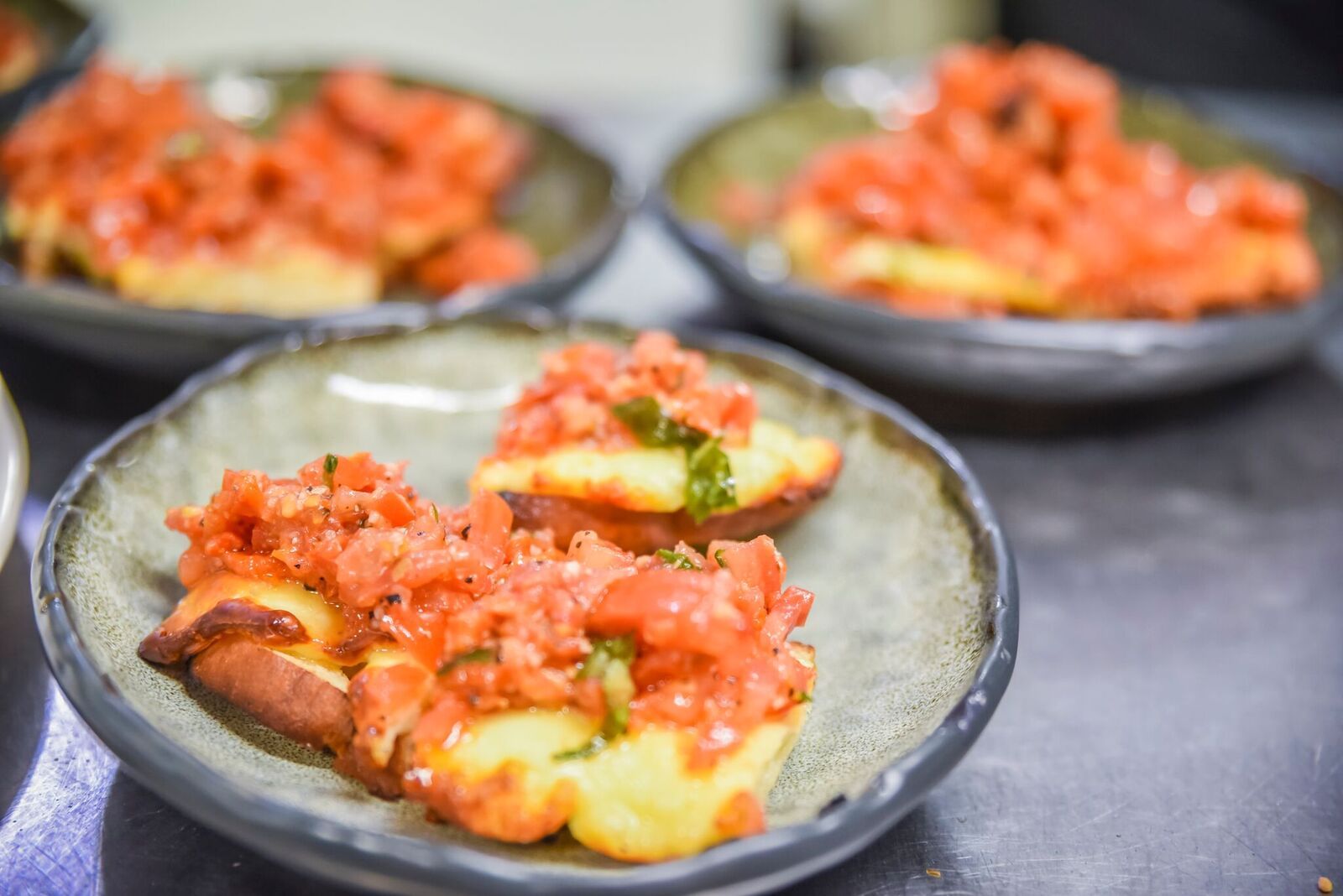 Bowls of salmon and avocado topped with red salsa on a dark table