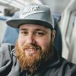 A man with a beard wearing a nike hat